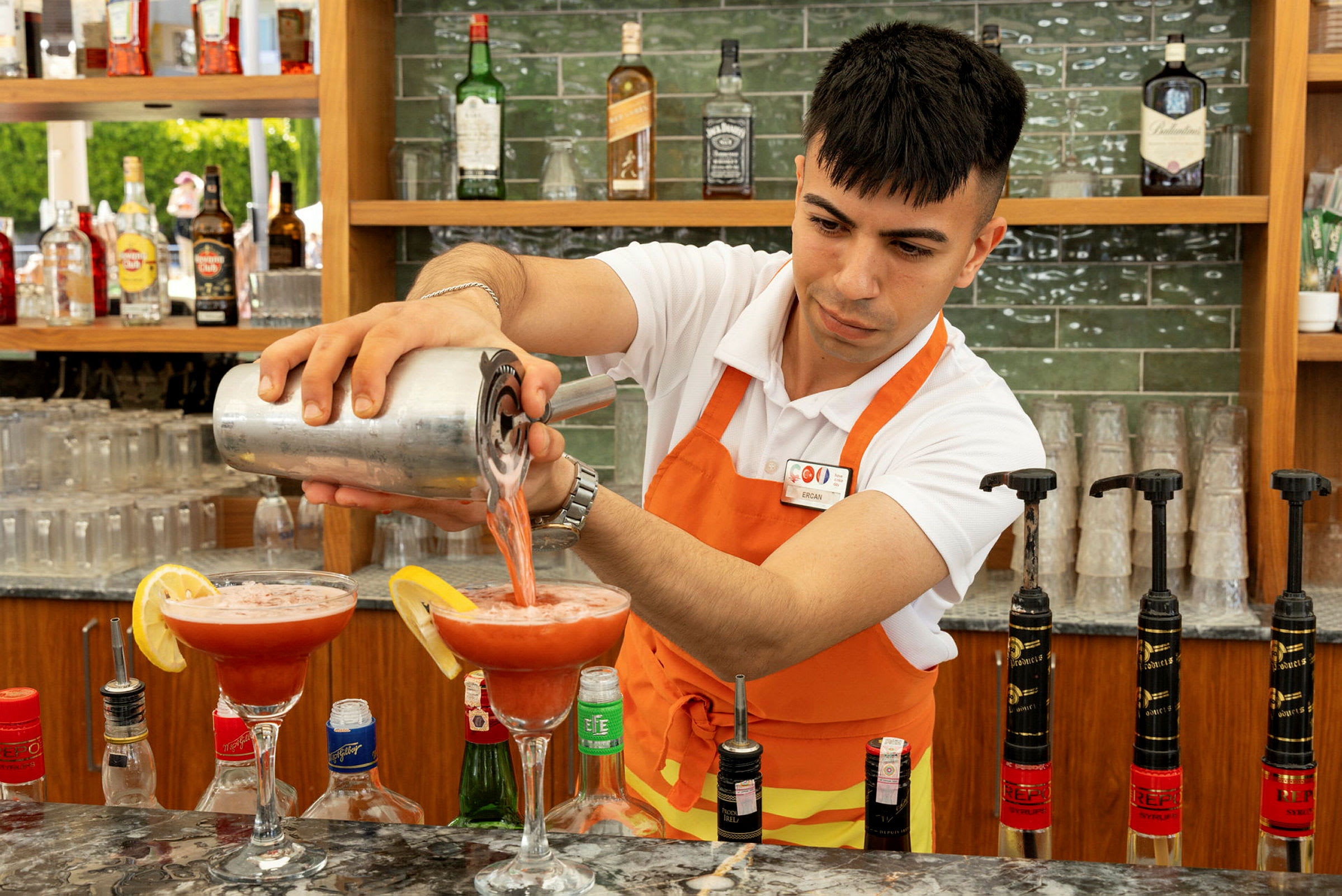 En bartender häller upp en röd dryck i cocktailglas. (AI-genererad text)