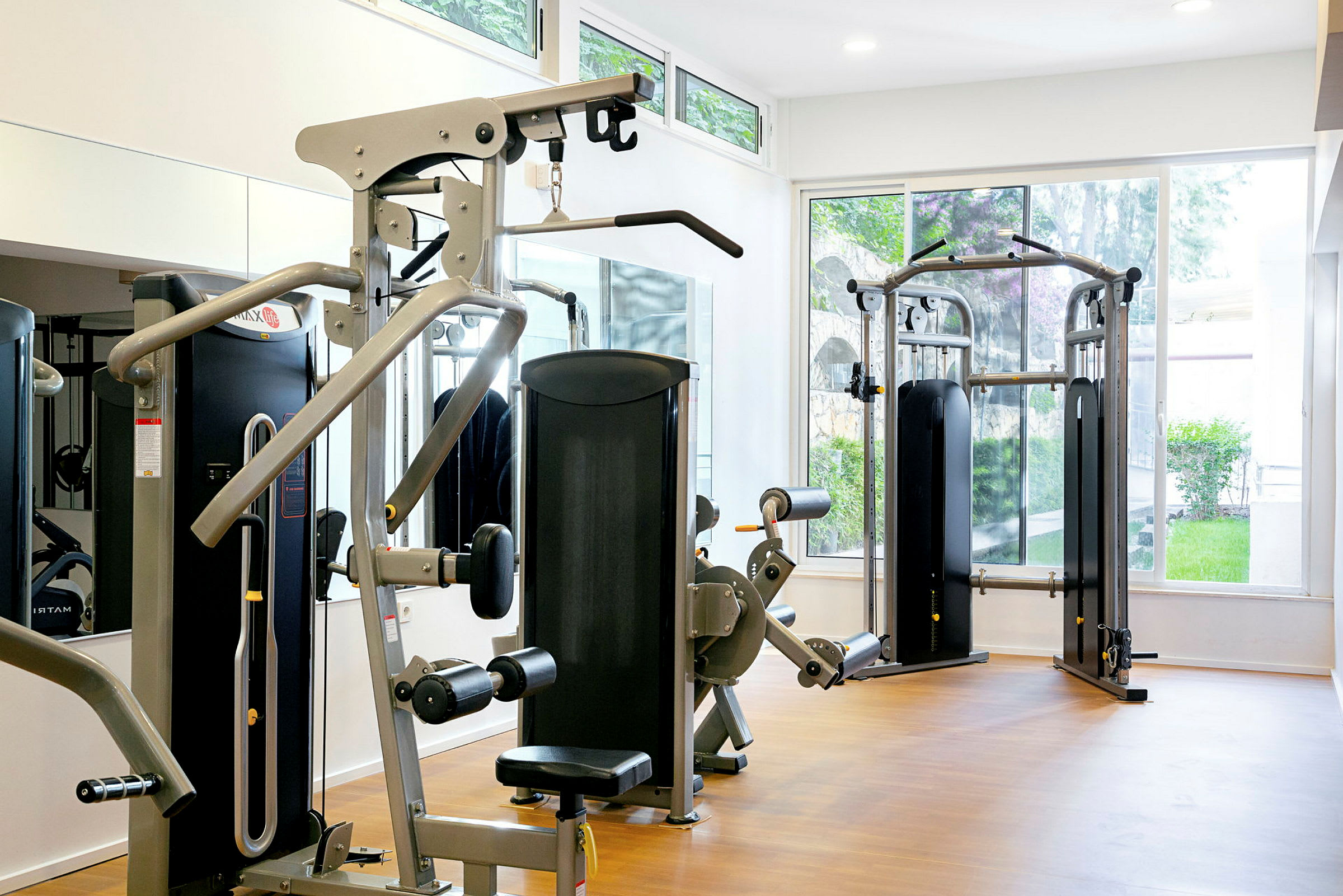 Ett gym med träningsmaskiner och stora fönster. (AI-genererad text)