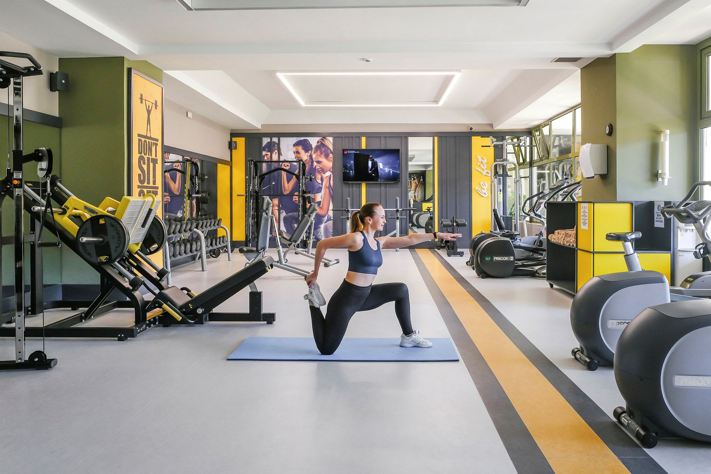 En kvinna utför stretchövningar på en träningsmatta i ett gym. (AI-genererad text)