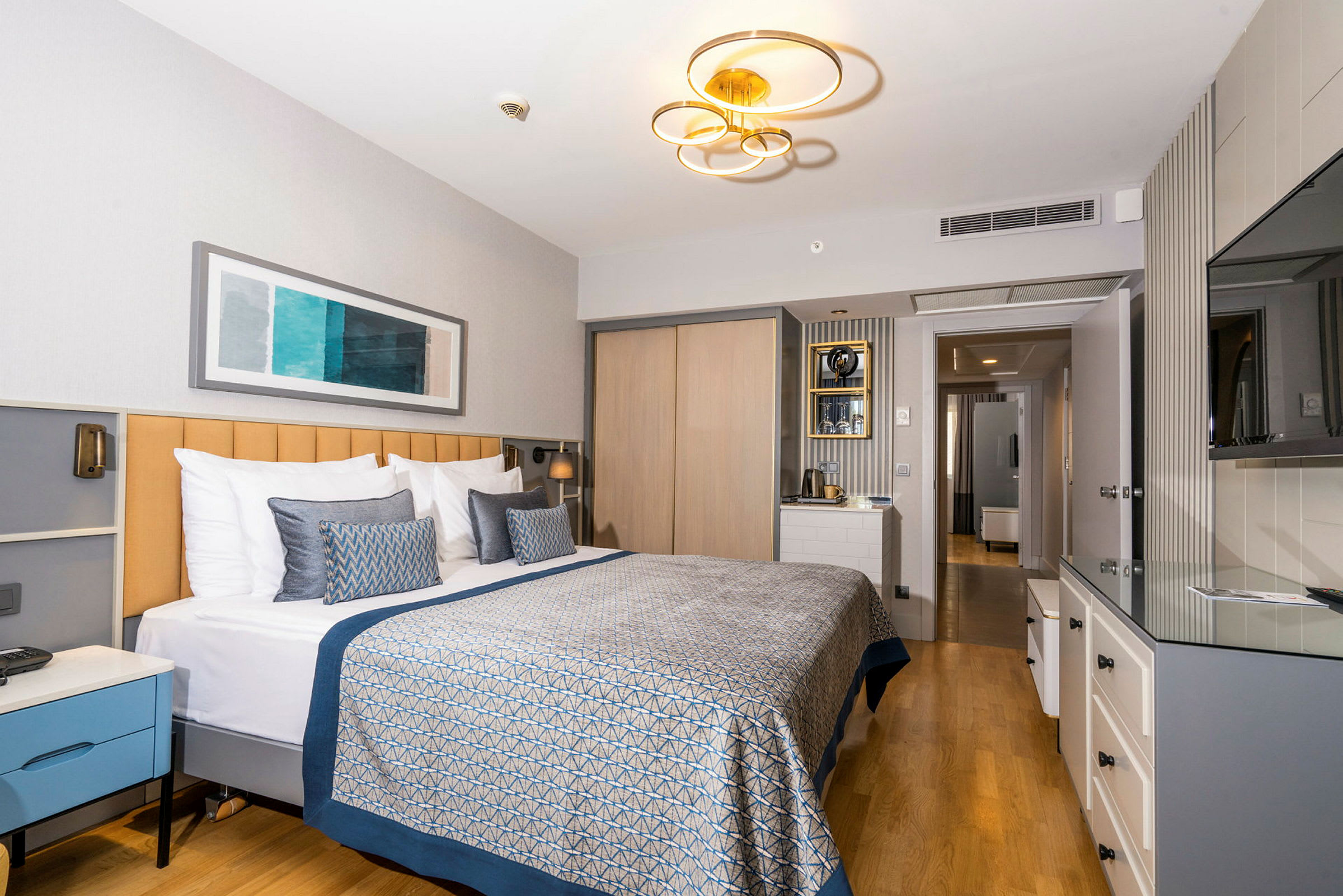 Modernt hotellrum med en stor dubbelsäng, ljus inredning och ett trägolv. (AI-genererad text)