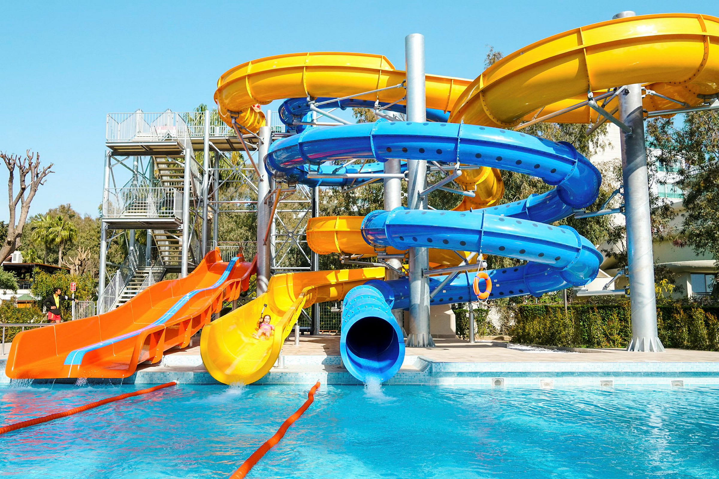 En vattenpark med färgglada vattenrutschbanor vid en pool. (AI-genererad text)