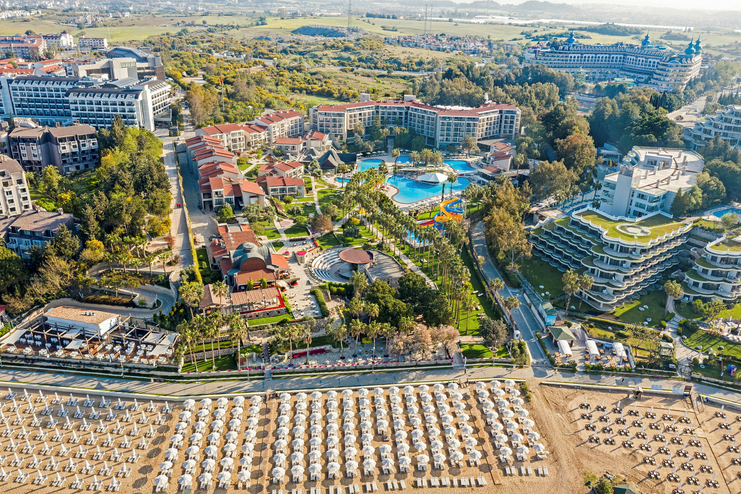 Hotellkomplex med pool, trädgårdar och strand med solstolar och parasoller. (AI-genererad text)