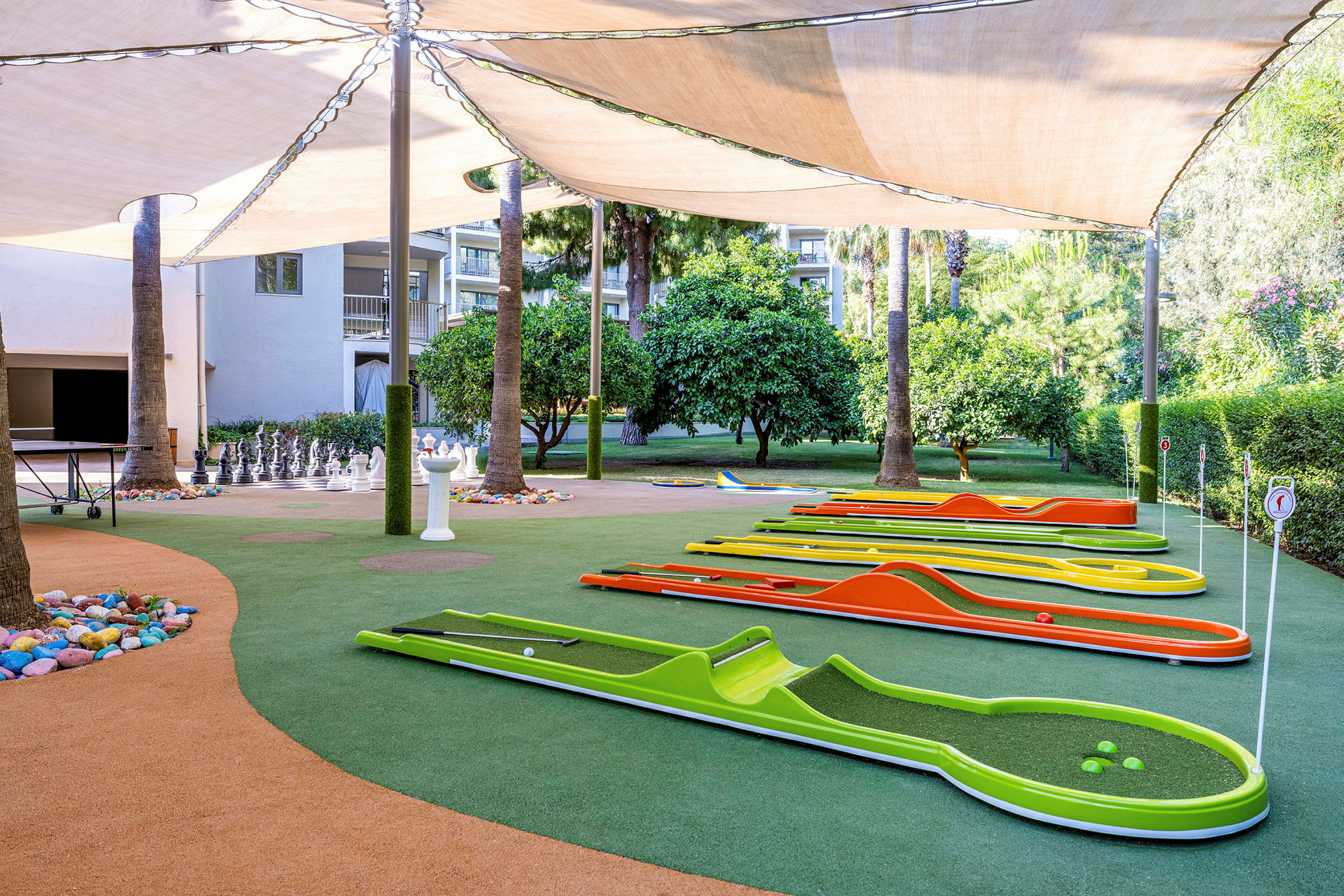 Minigolfbana med färgglada banor och ett schackspel under en baldakin. (AI-genererad text)