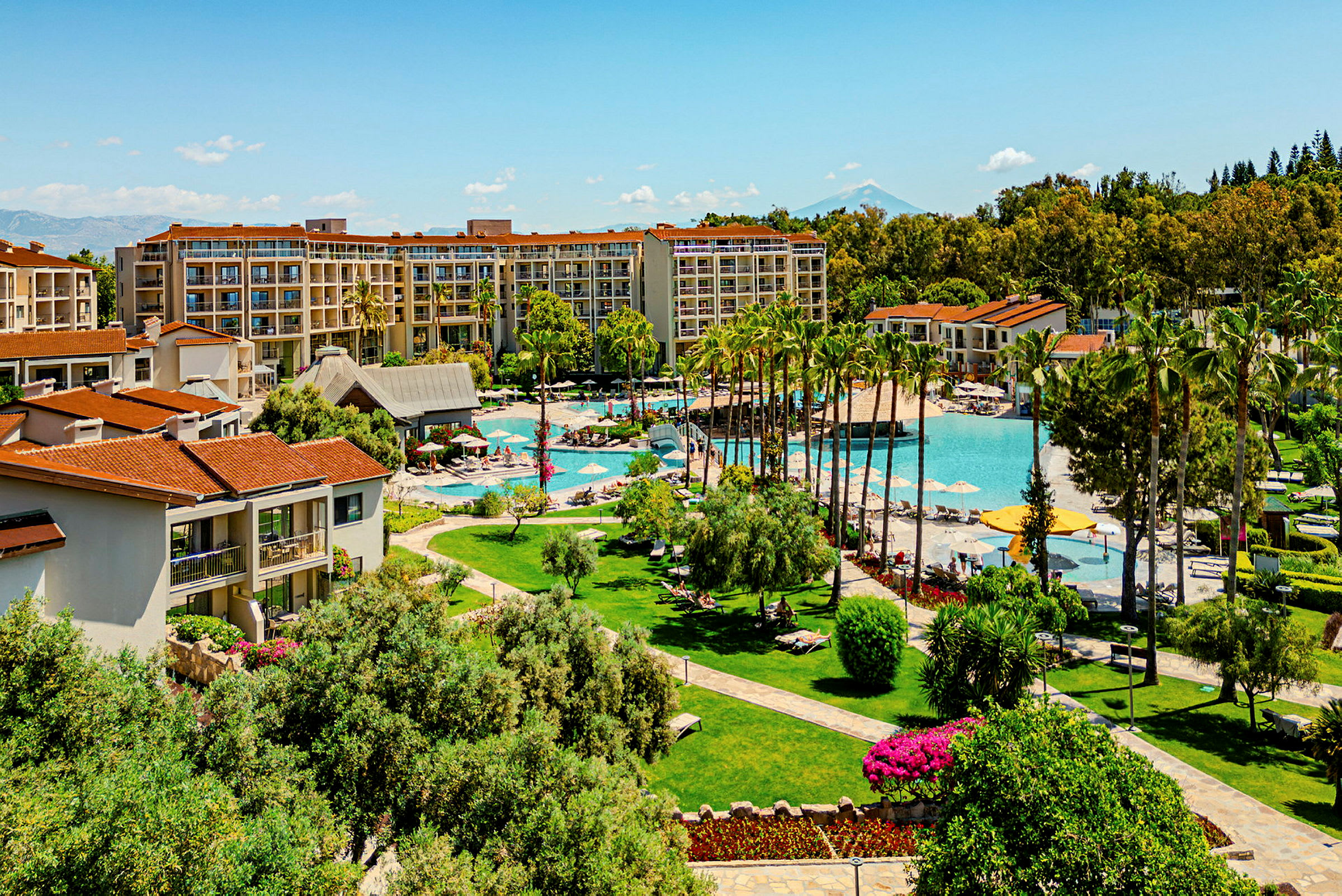 Bild av hotellbyggnader vid en pool omgivet av grönskande trädgårdar. (AI-genererad text)
