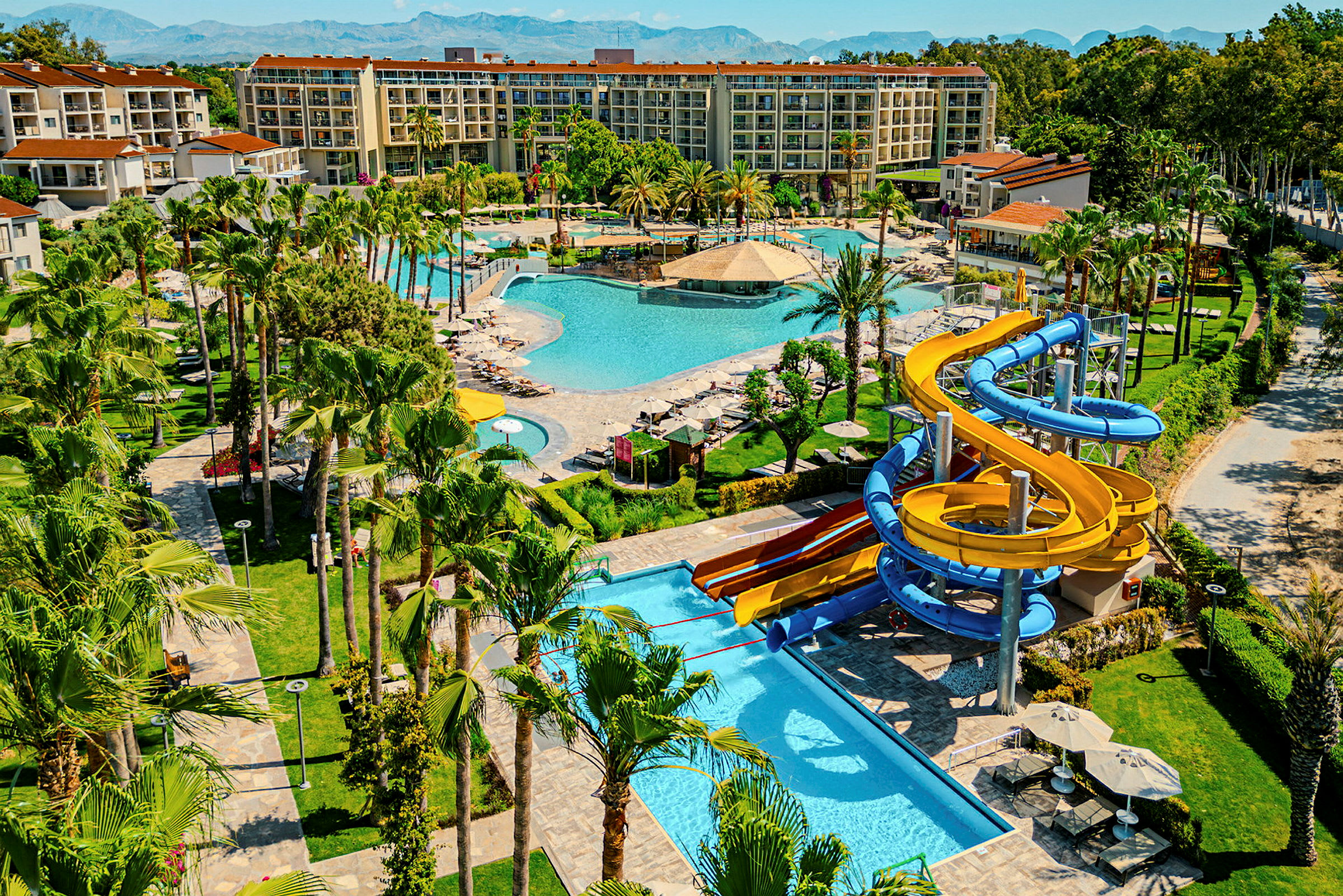 En resort med flera pooler, grönområden och vattenrutschkanor. (AI-genererad text)