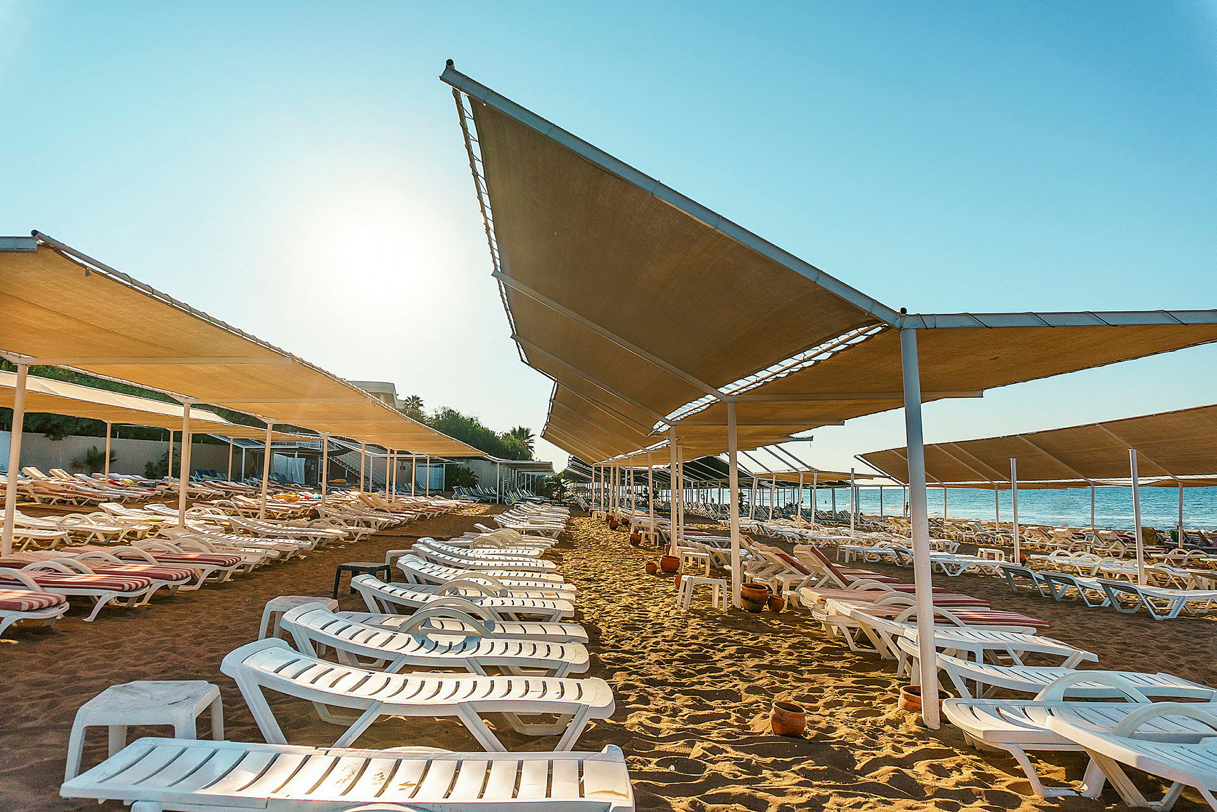 Solstolar och skuggande tak på en strand vid havet. (AI-genererad text)