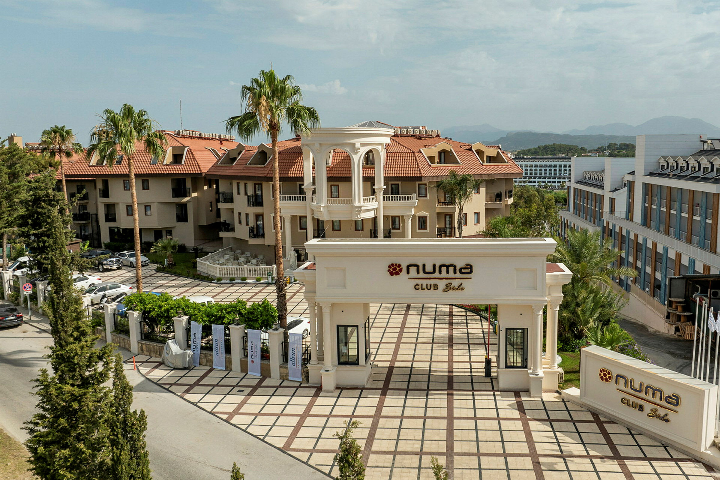 Bild som visar den främre entrén till Numa Club med omgivande byggnader och träd. (AI-genererad text)