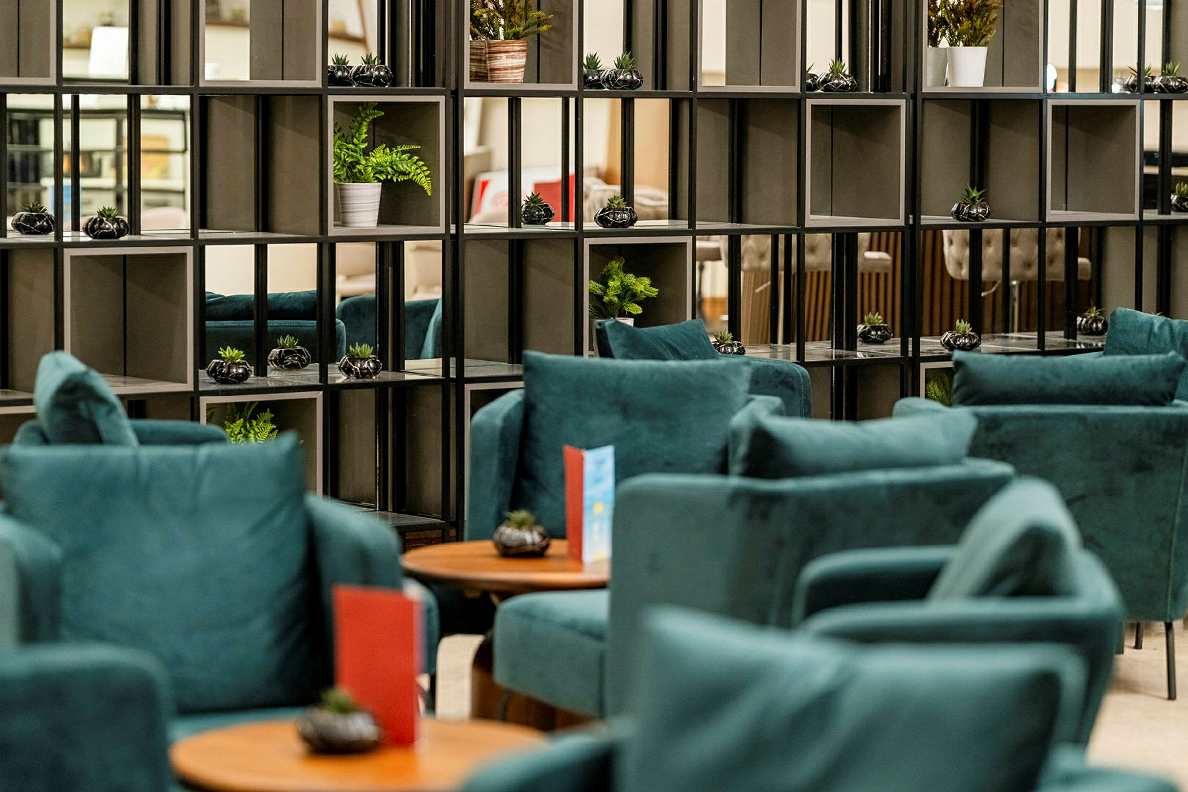 En lounge med blå fåtöljer och hyllor med dekorativa växter. (AI-genererad text)