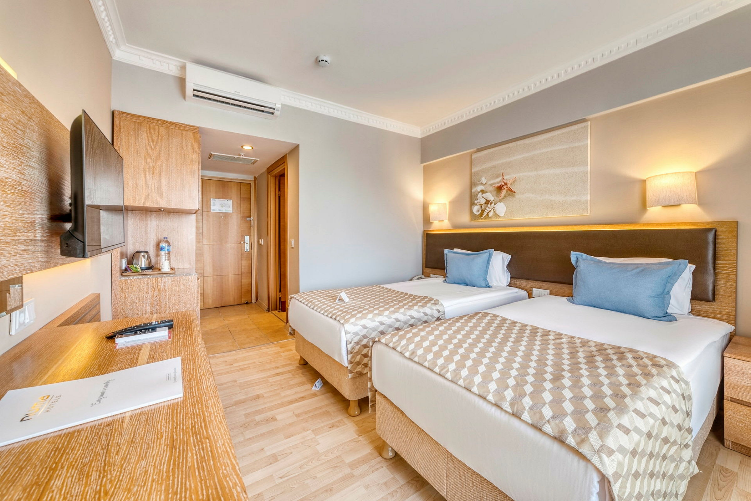 Hotellrum med två enkelsängar, en skrivbord och en dörr till badrummet. (AI-genererad text)