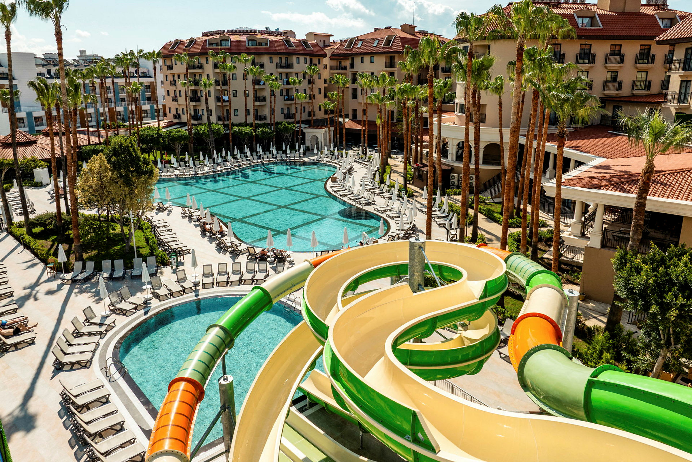 Bild av ett hotellområde med pool, solstolar och en vattenrutschbana. (AI-genererad text)