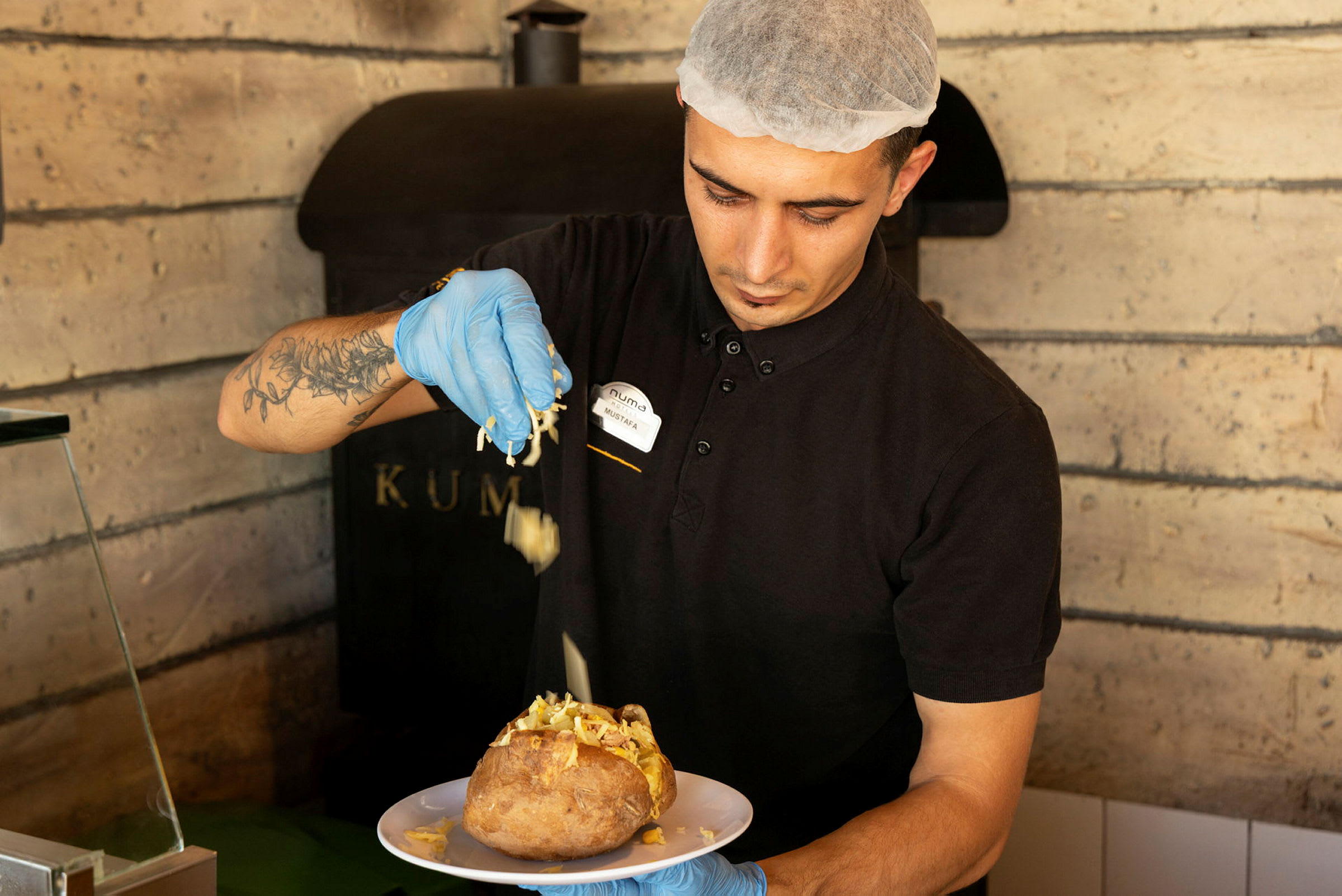 En person lägger topping på en bakad potatis. (AI-genererad text)