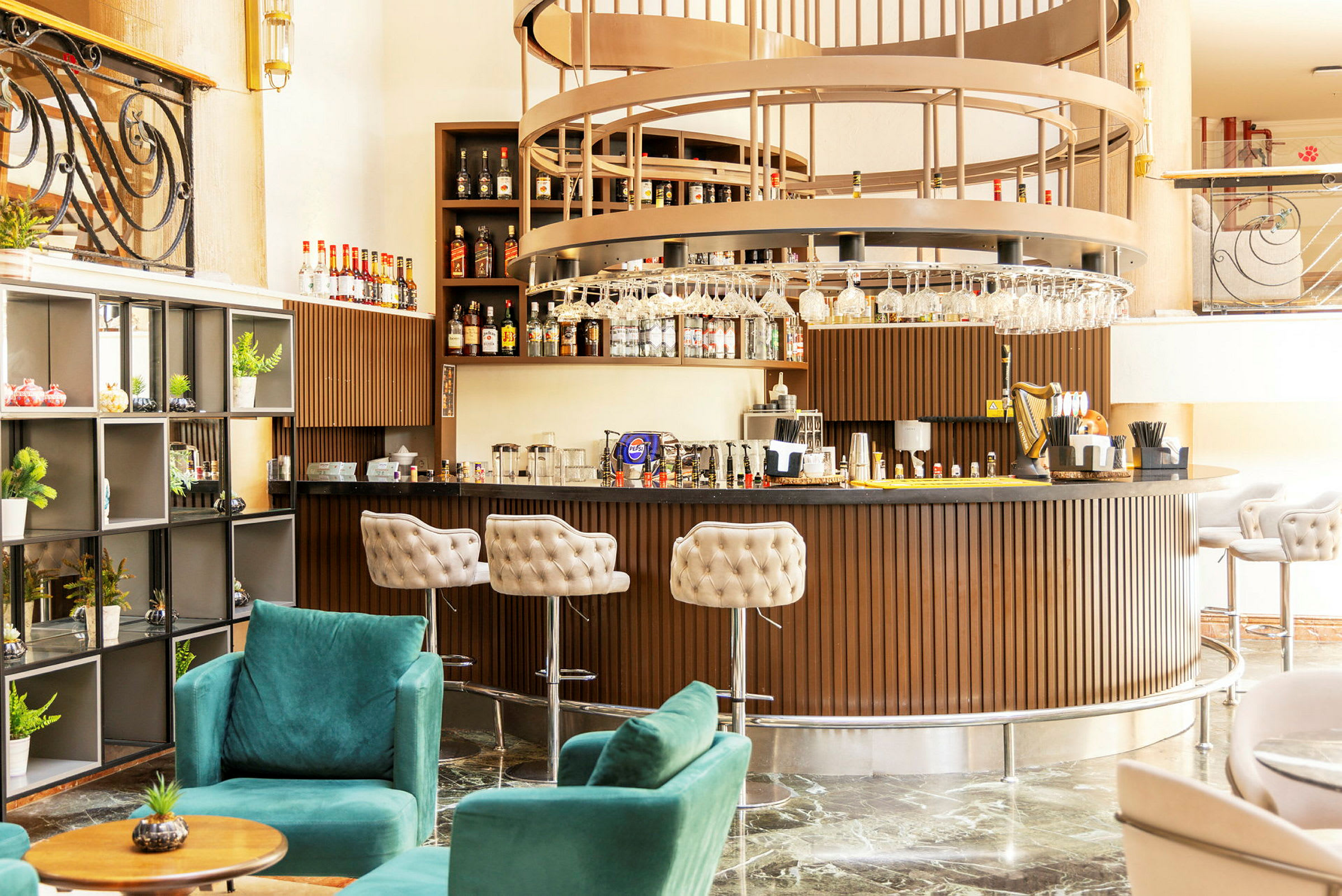 En stilfull hotellbar med elegant inredning, inklusive gröna fåtöljer och en rund bardisk i trädesign. (AI-genererad text)