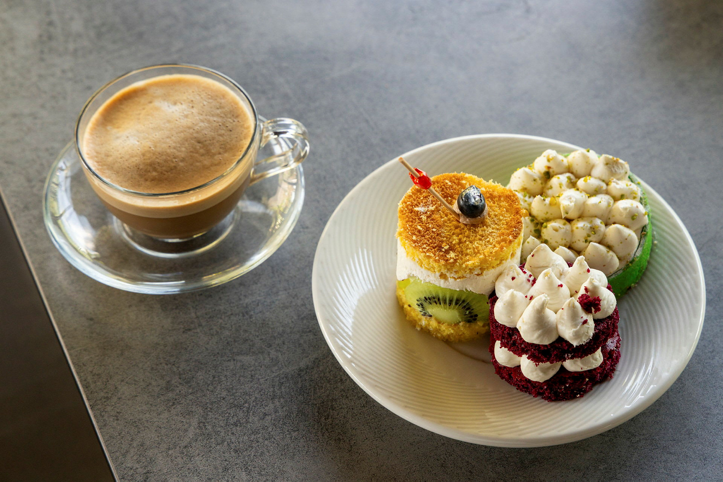 En kopp med kaffe bredvid en tallrik med tre delikata bakverk. (AI-genererad text)