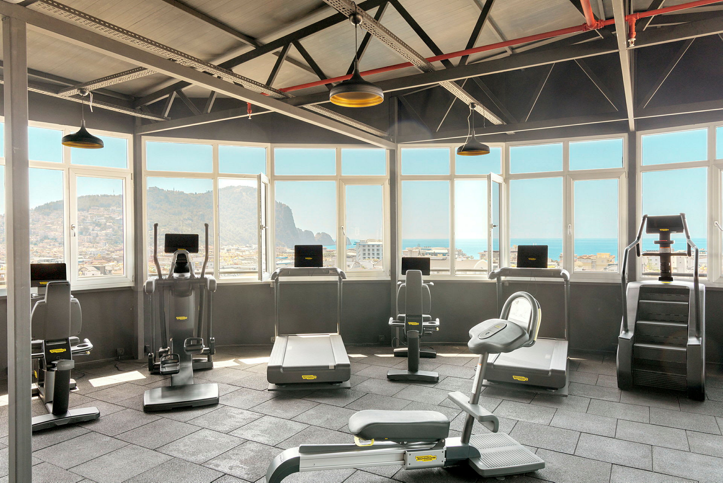 Gym med träningsmaskiner och utsikt genom fönster. (AI-genererad text)