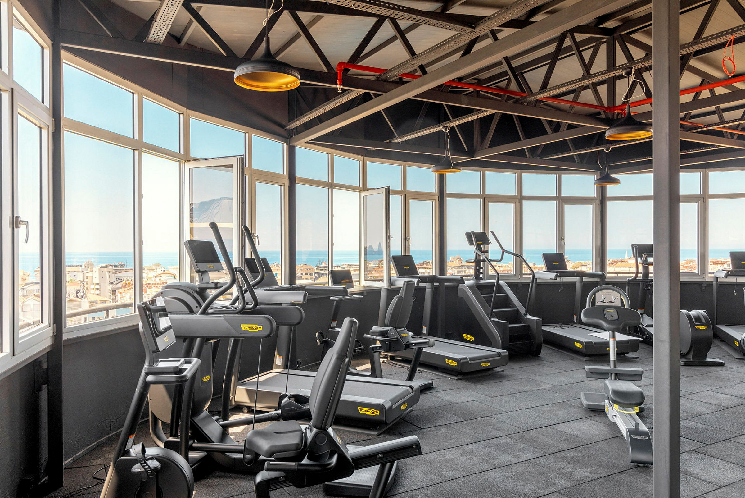 Ljusa gym med träningsmaskiner och utsikt genom stora fönster. (AI-genererad text)