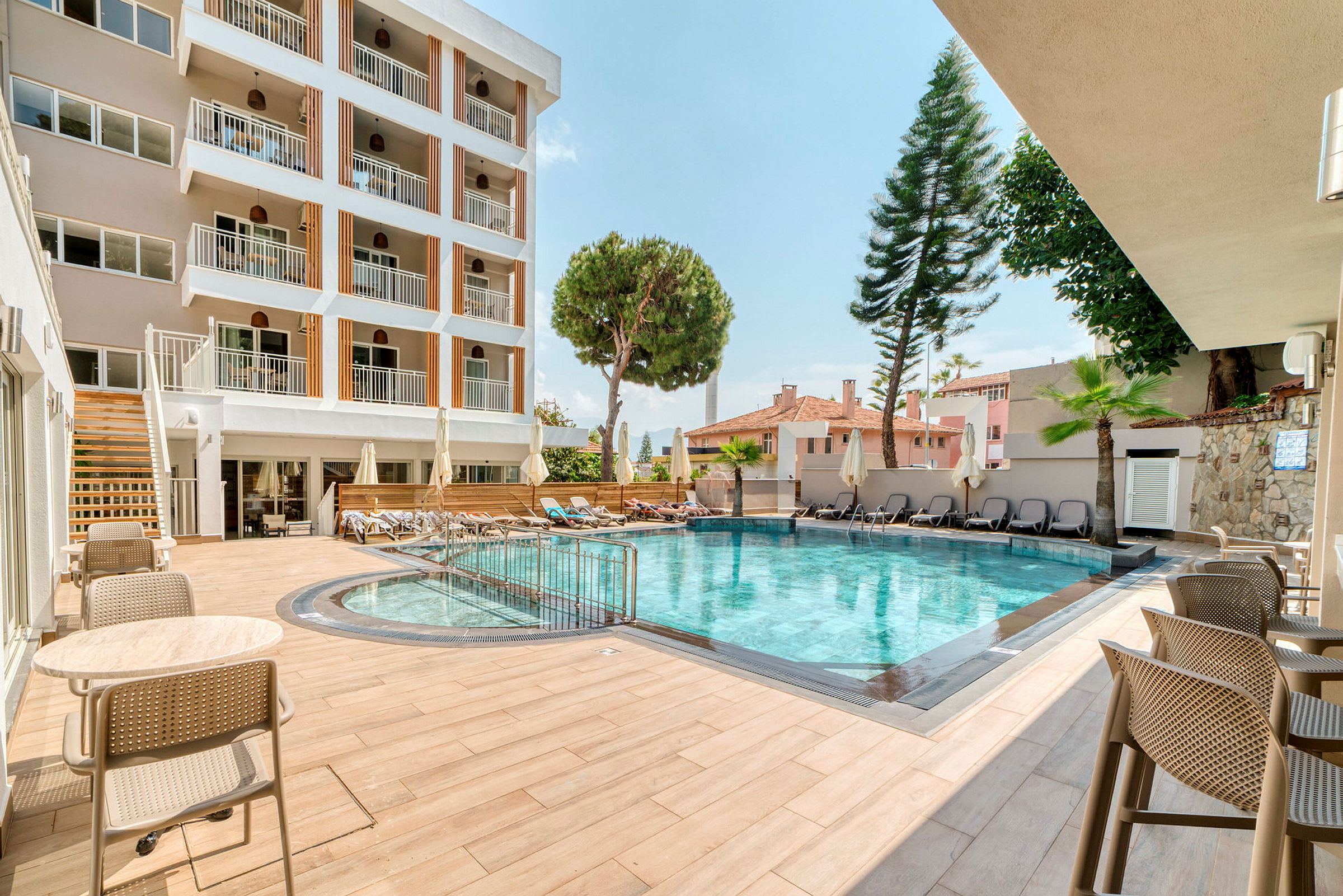 Hotellets utomhuspool med sittmöbler och solstolar. (AI-genererad text)