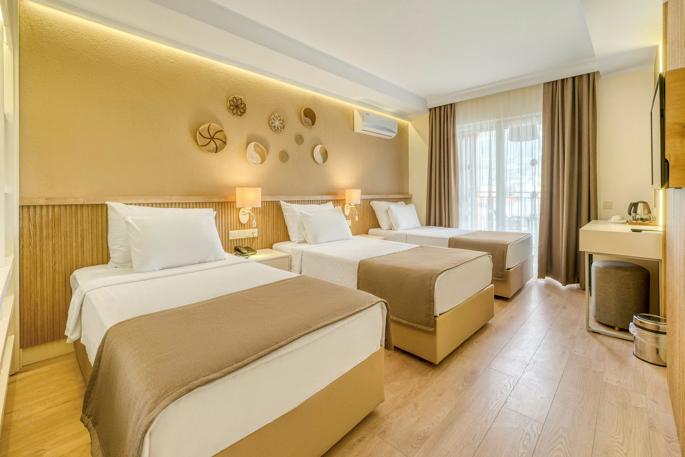 Ett hotellrum med tre enkelsängar, en skrivbordshörna och dekorationer på väggen. (AI-genererad text)