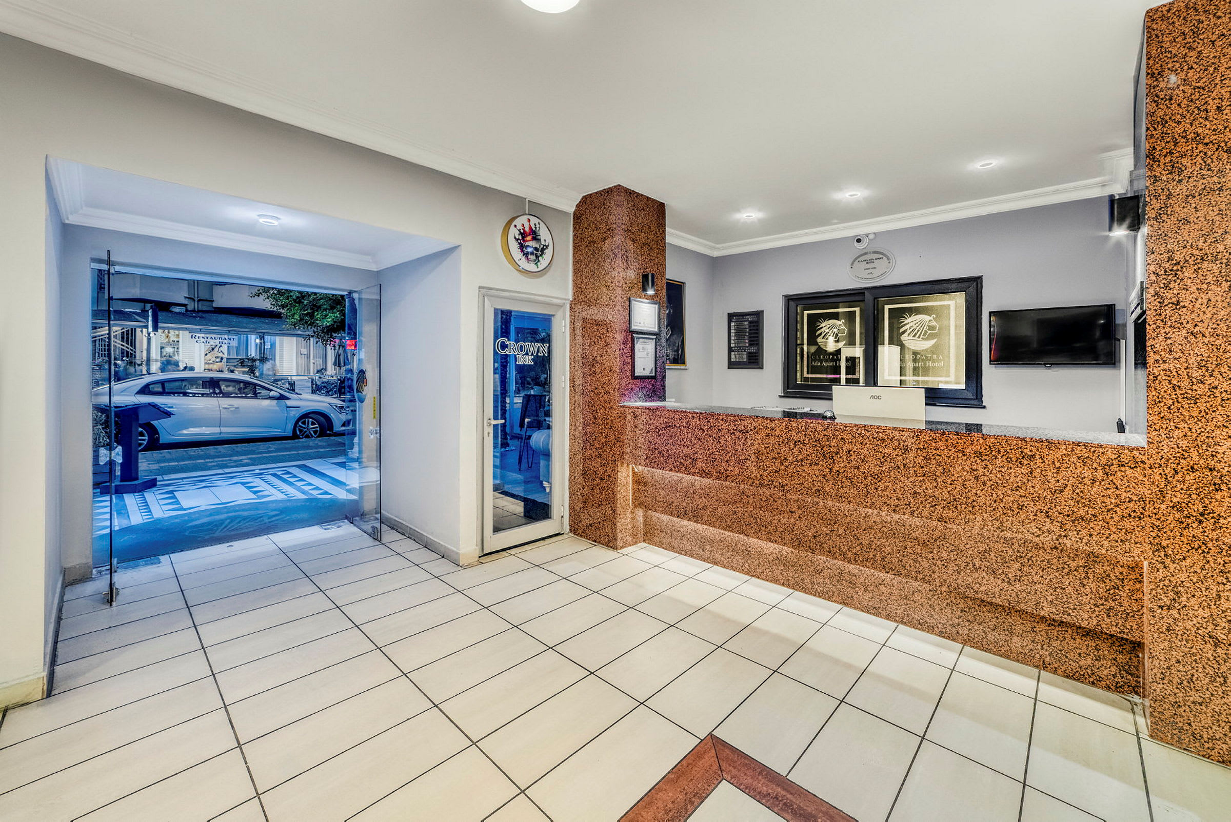 Entréområdet med receptionsdisk, hotellskylt och glasdörrar som leder ut mot gatan. (AI-genererad text)