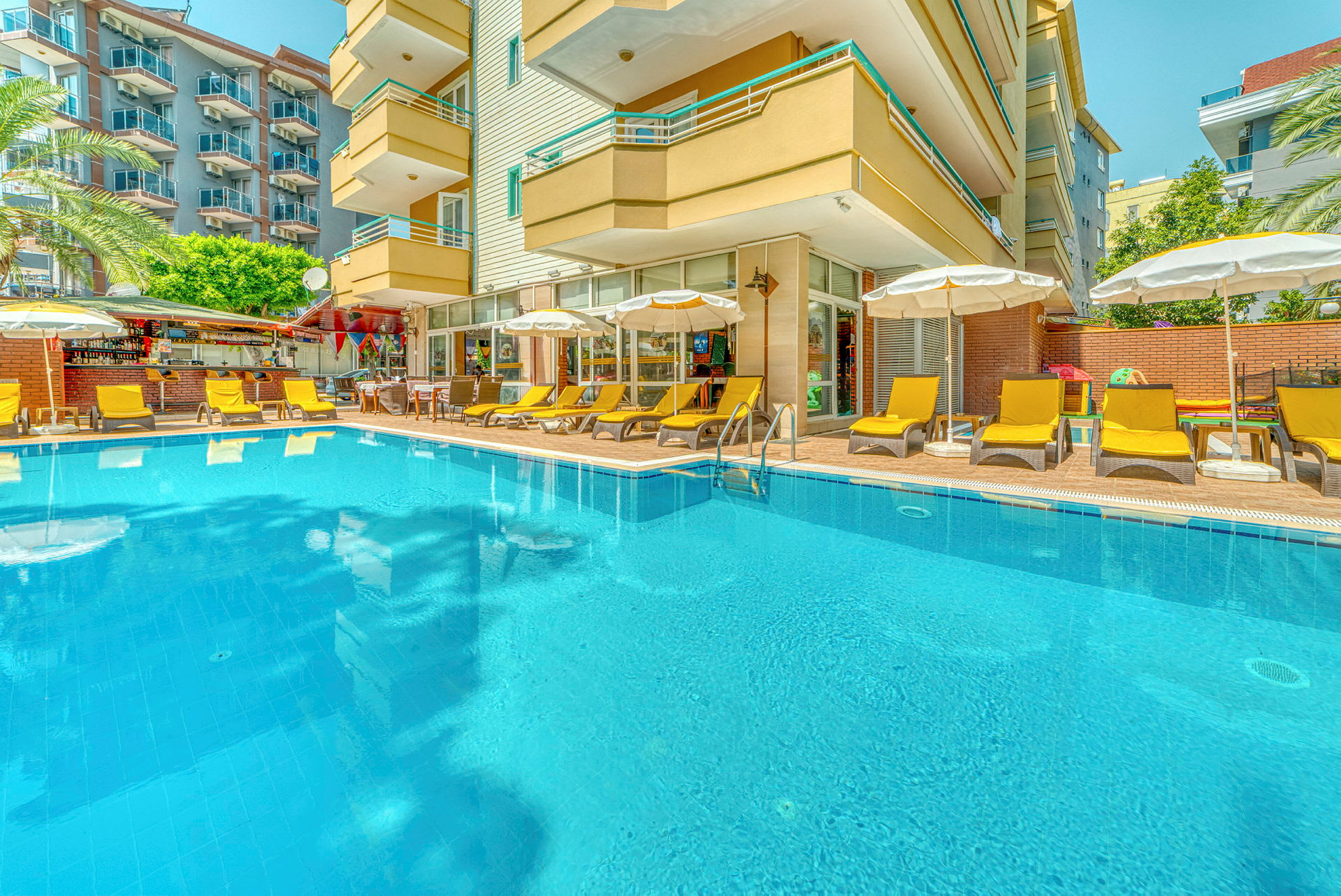 En utomhuspool omgiven av solsängar och parasoller vid ett hotell. (AI-genererad text)