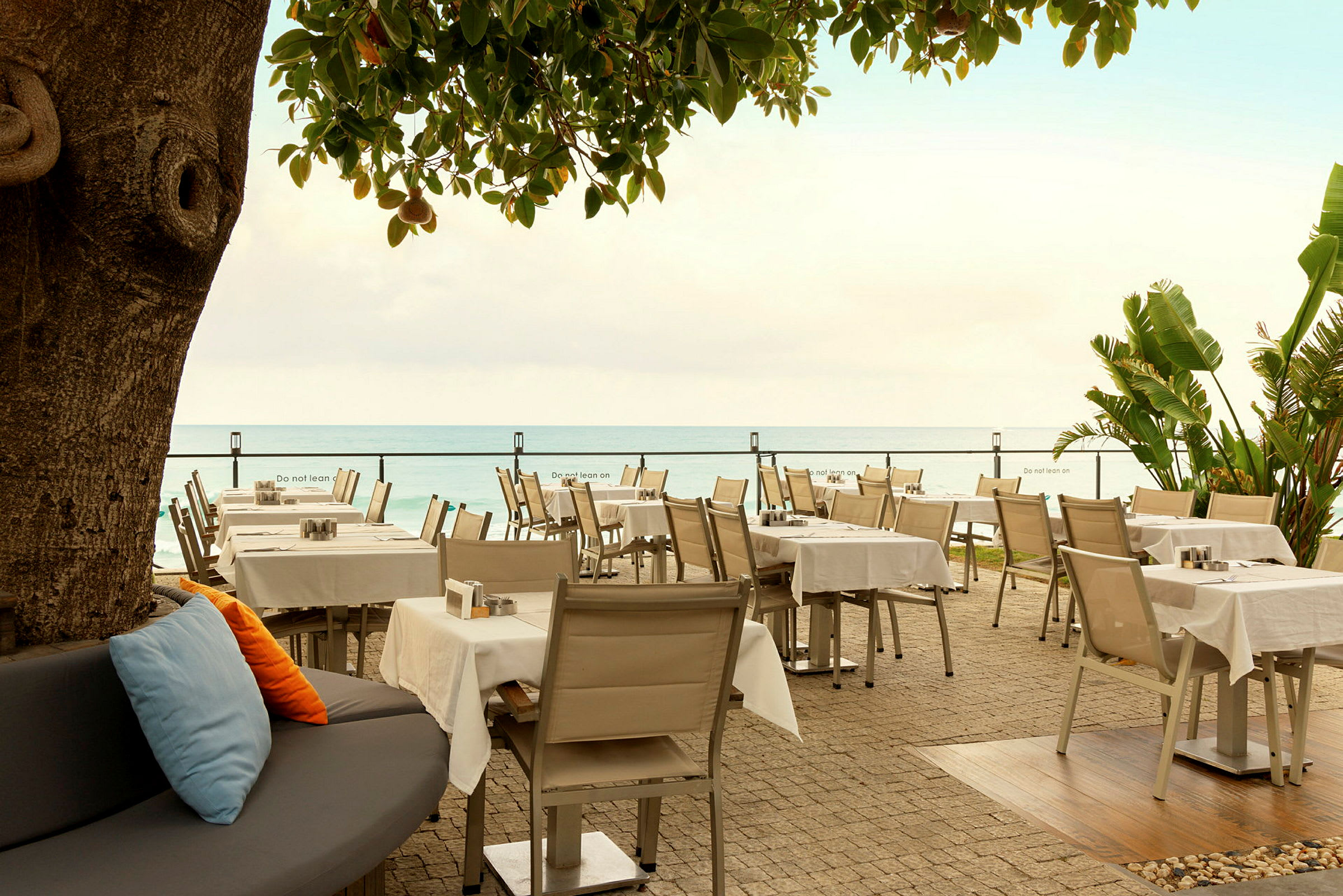 Restaurang med bord och stolar vid havet. (AI-genererad text)