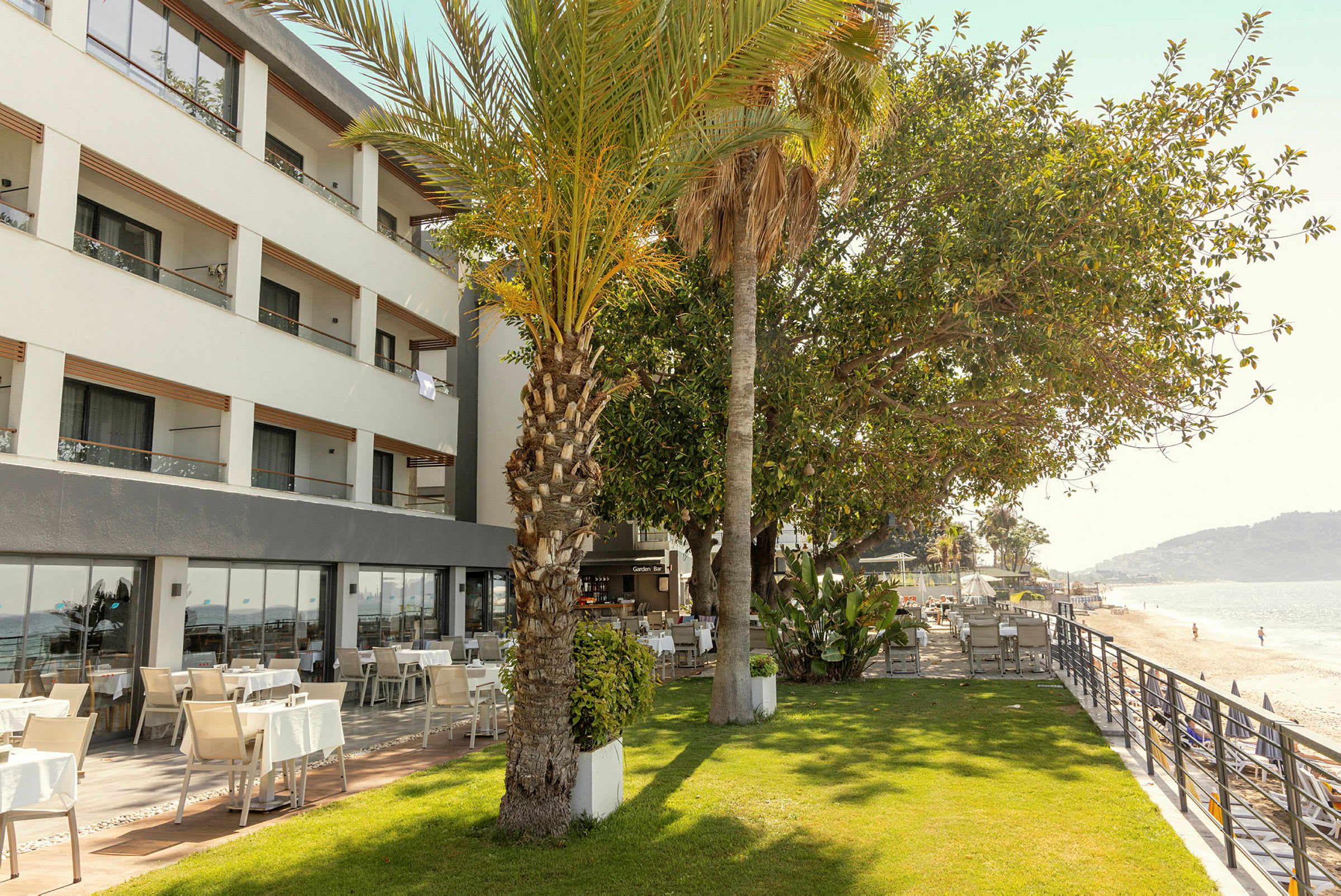 Hotell med utomhusutsikt över en grön gräsmatta och en strand. (AI-genererad text)