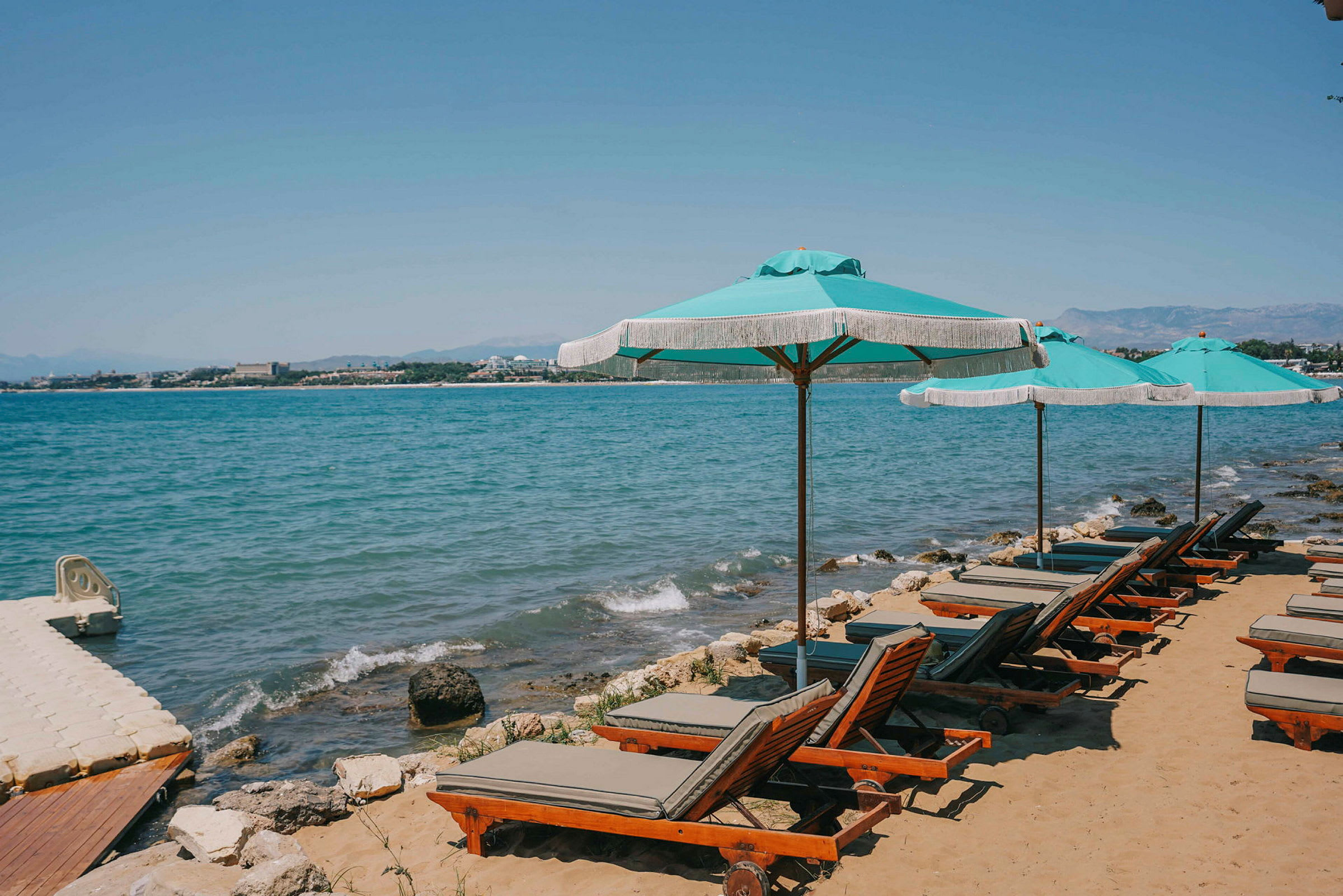 Strand med solstolar och parasoller vid havet. (AI-genererad text)