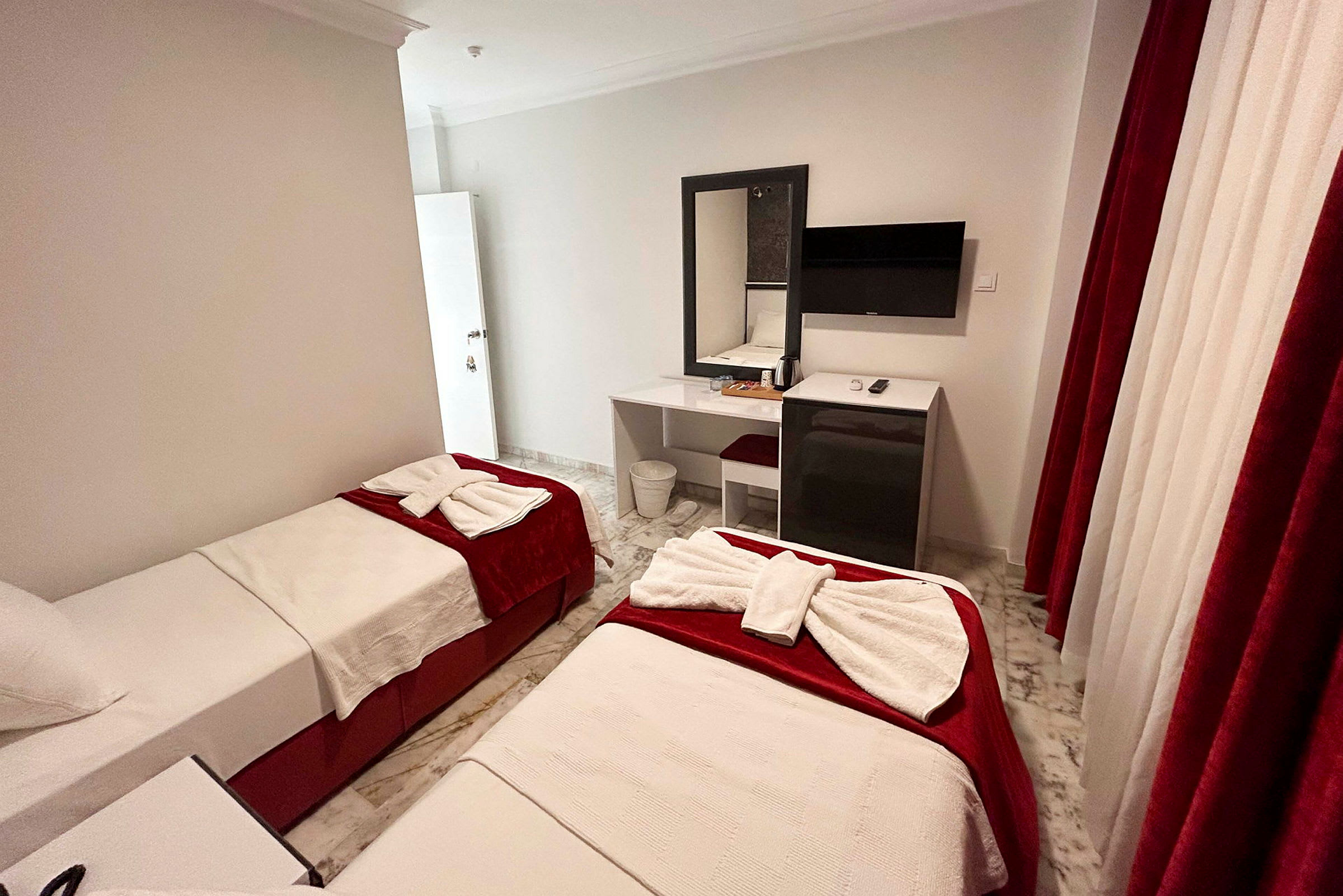 Hotellrum med två enkelsängar, skrivbord, och TV. (AI-genererad text)