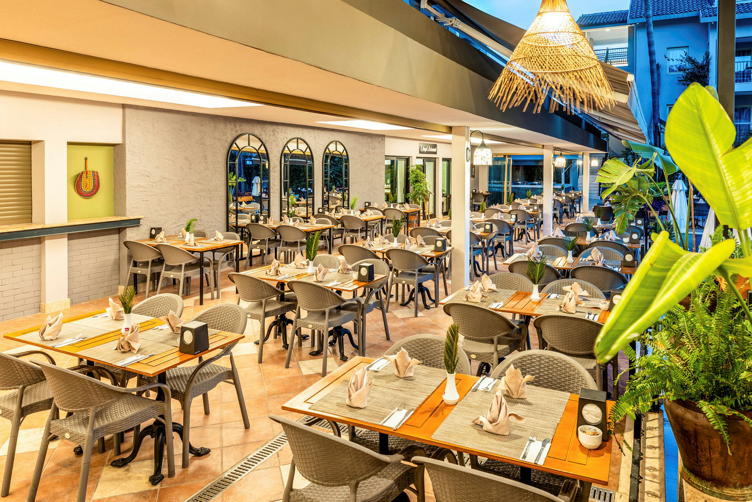 En restaurangmiljö med dukade bord och stolar, dekorerade med växter och välplacerade servetter. (AI-genererad text)