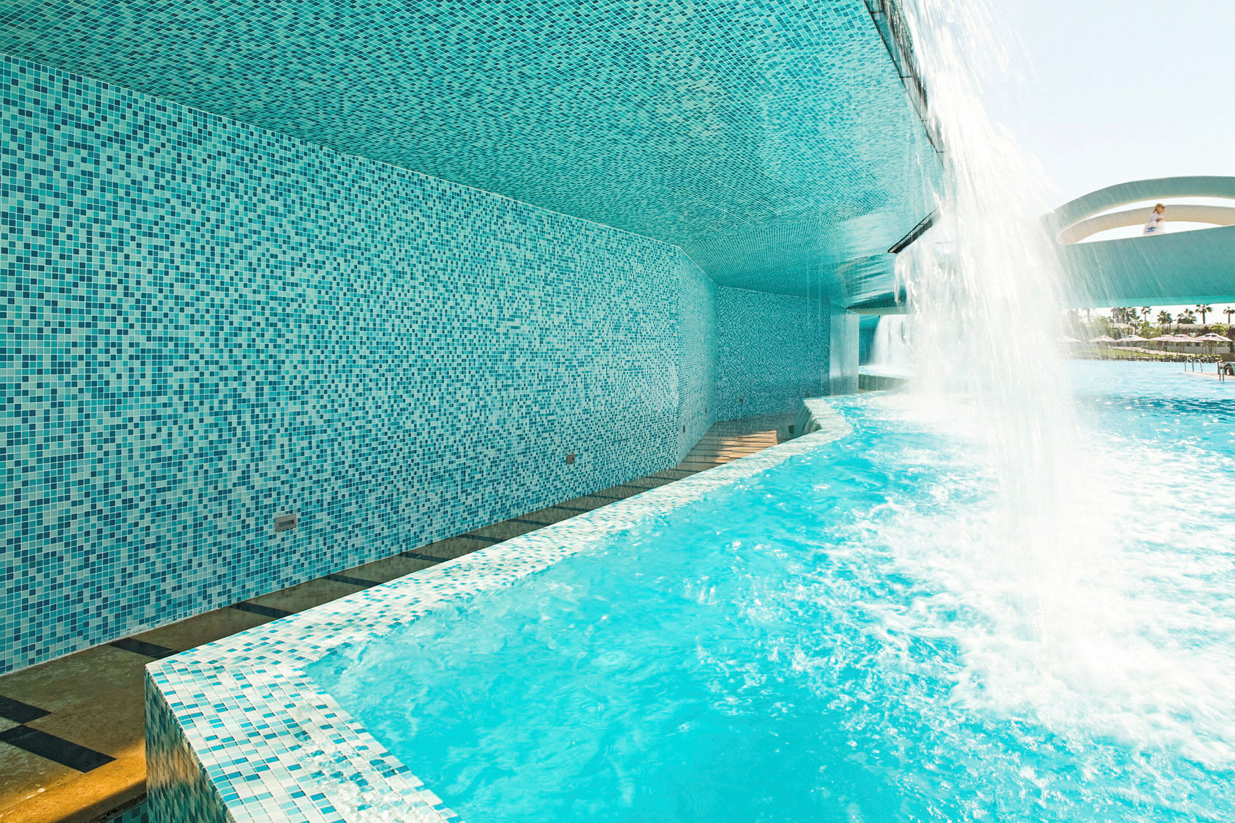 En pool med vattenfall och mosaikväggar. (AI-genererad text)