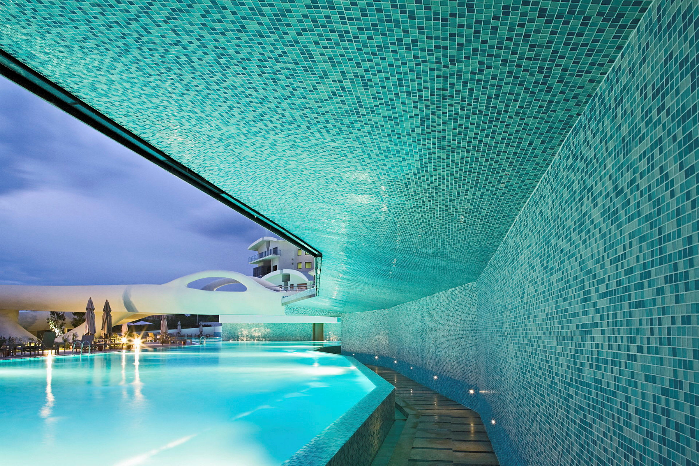Mosaikklädd pool med bågformade byggnadsdetaljer och kvällsbelysning. (AI-genererad text)