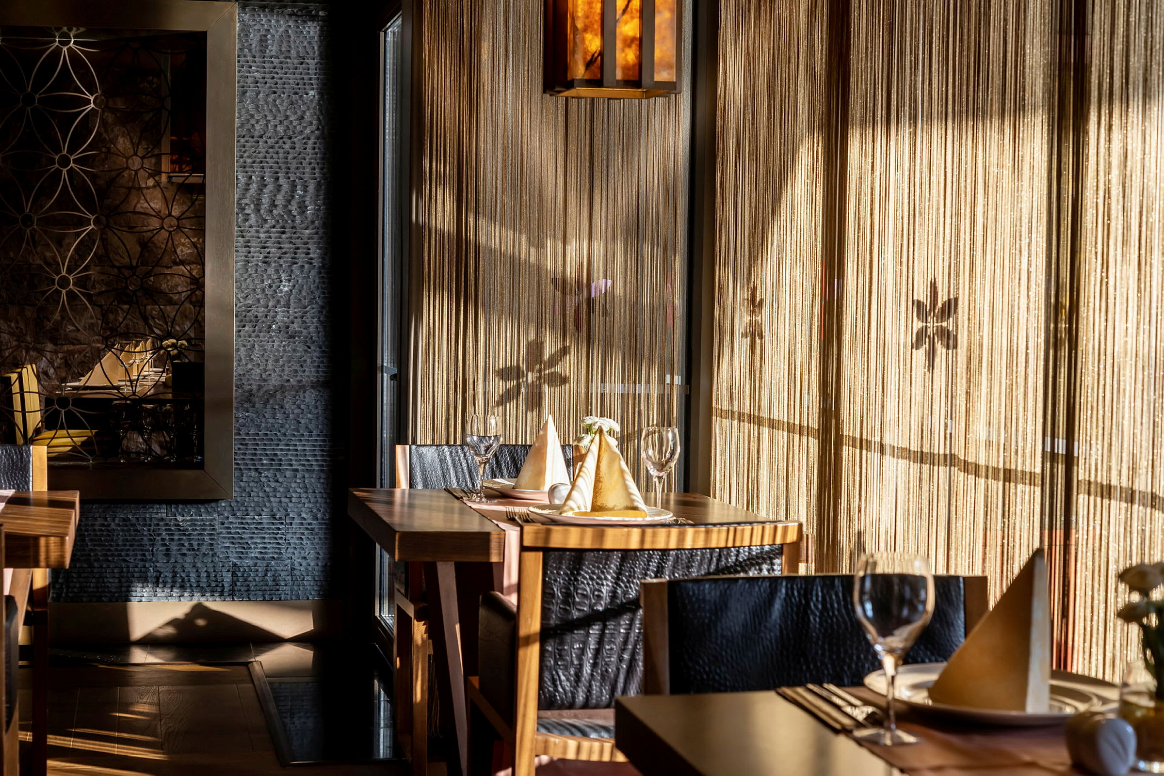 Interiör av en elegant restaurang med dukade bord, ljusinsläpp och dekorativa väggdetaljer. (AI-genererad text)