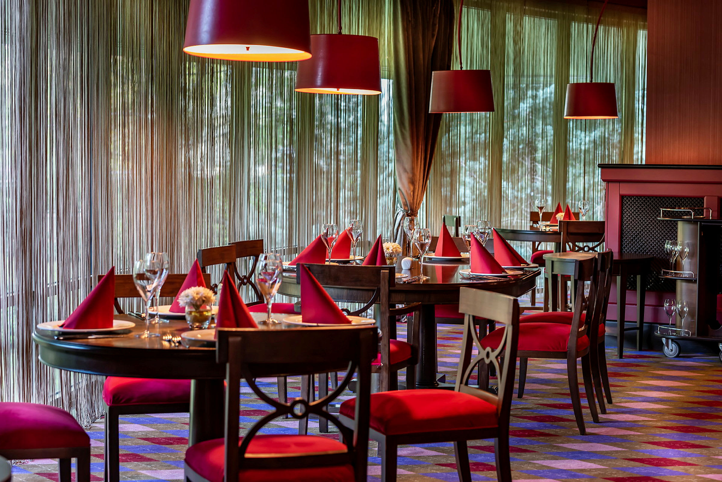 En elegant restaurang med bord dukade med röda servetter och glas. (AI-genererad text)