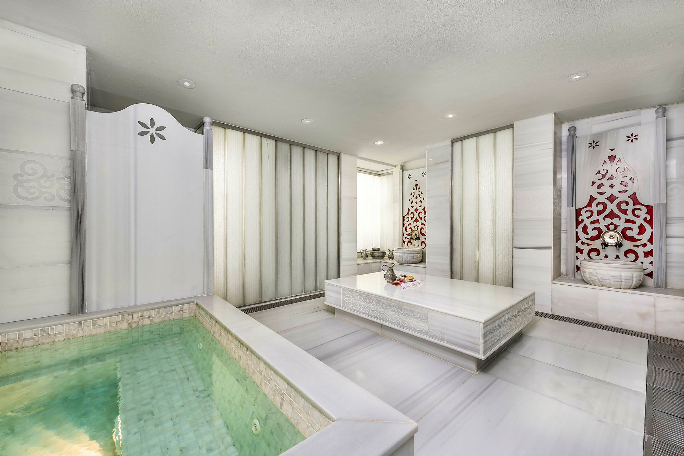 Ett spa-rum med en liten pool och dekorerade väggar. (AI-genererad text)