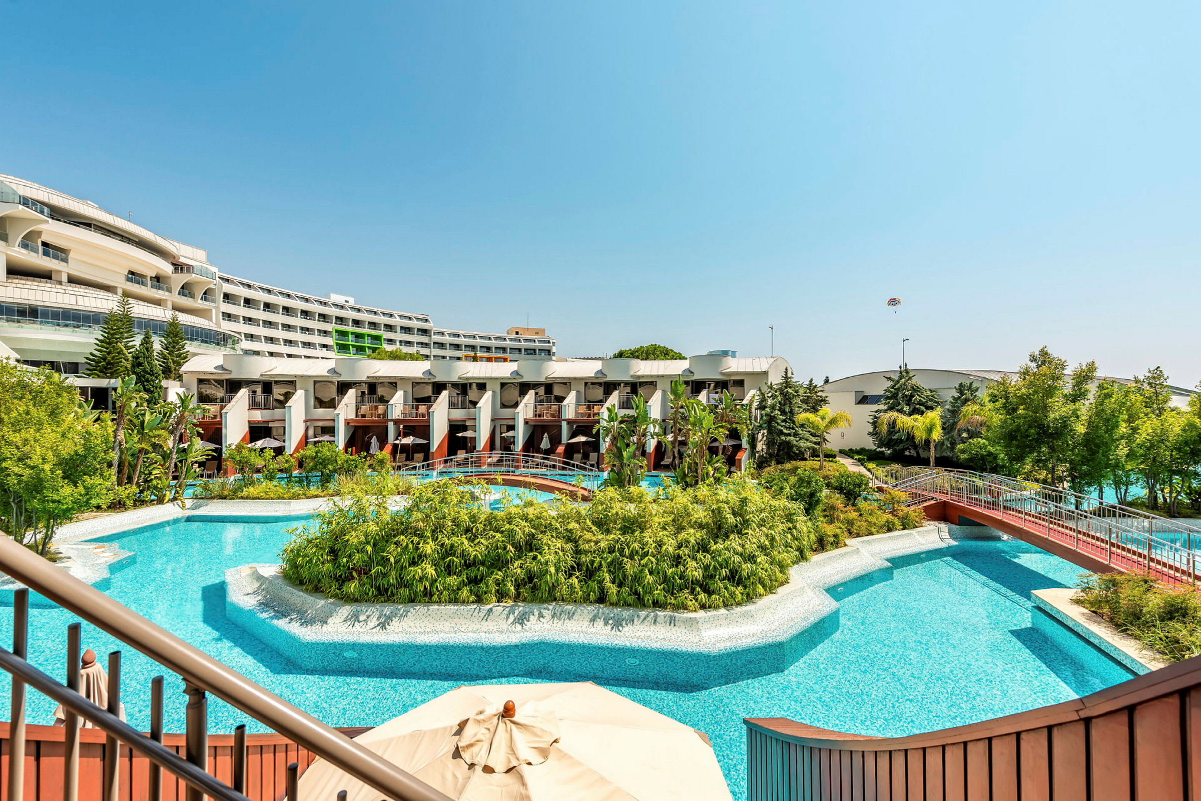 Bild av en hotellpool med grönskande växter och utsikt över byggnader i bakgrunden. (AI-genererad text)