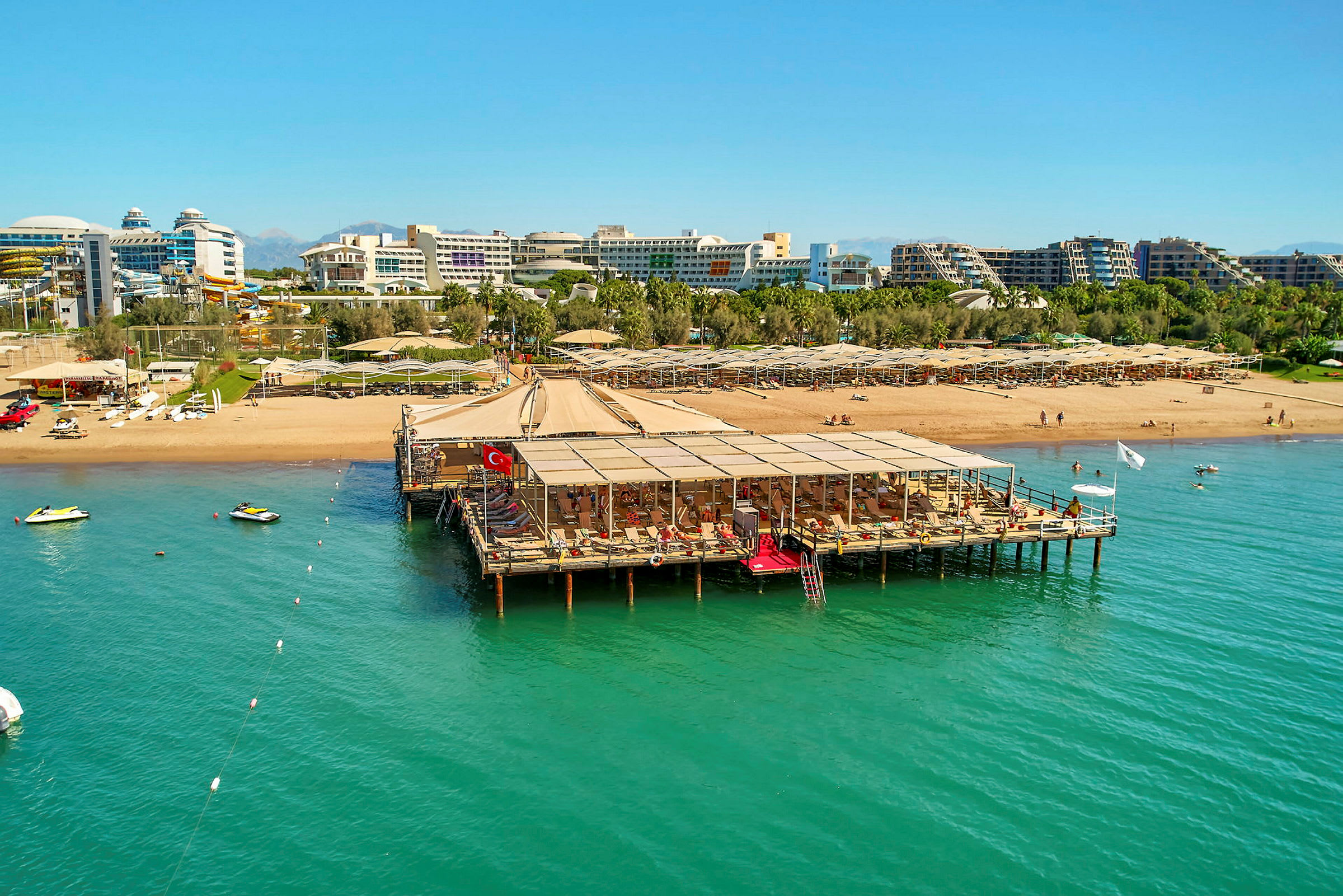 Strand med brygga, solsängar och hotell bakgrund. (AI-genererad text)