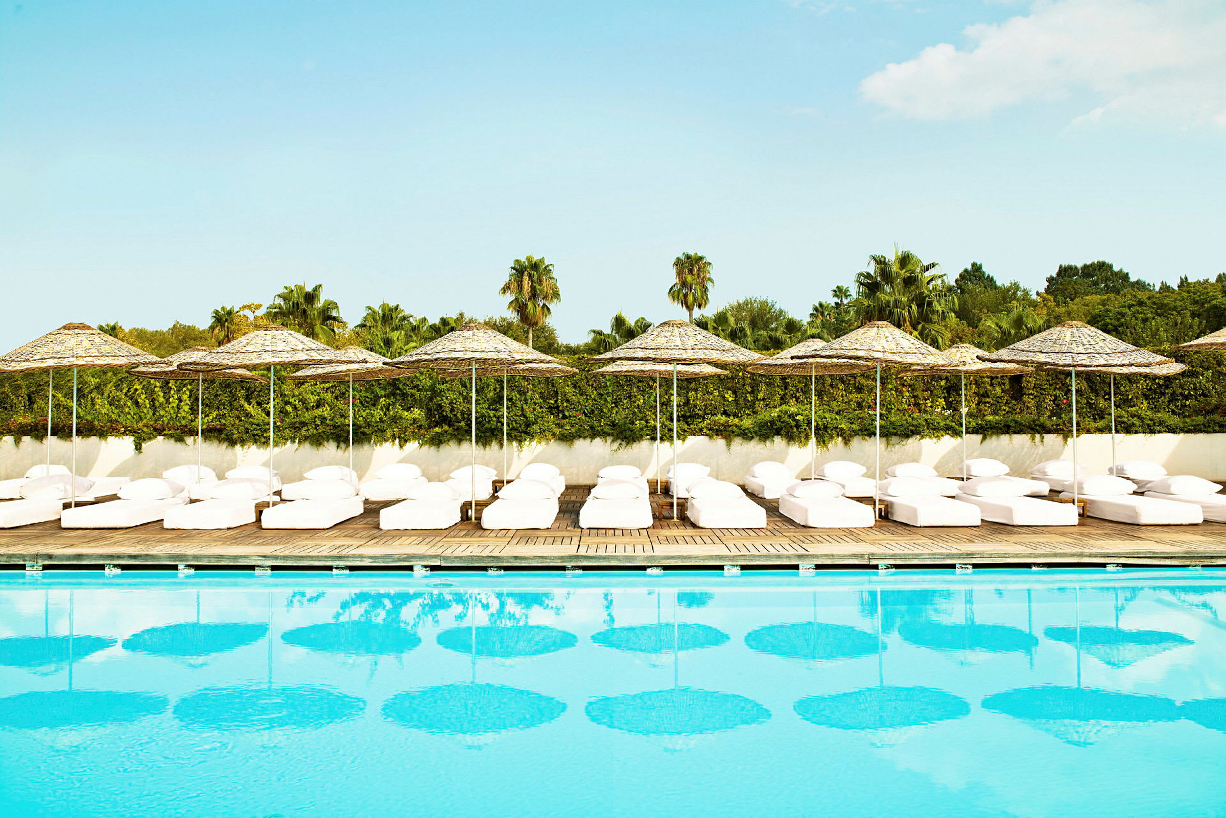 Pool med solstolar och parasoll i bakgrunden. (AI-genererad text)