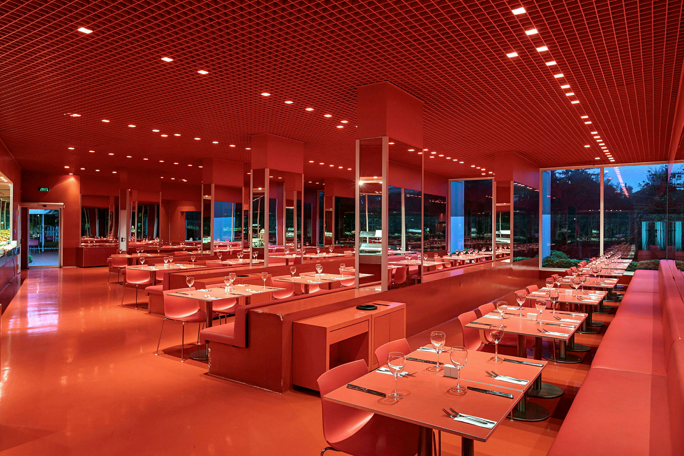 En modern restaurang med röd inredning, dukade bord och stora fönster. (AI-genererad text)