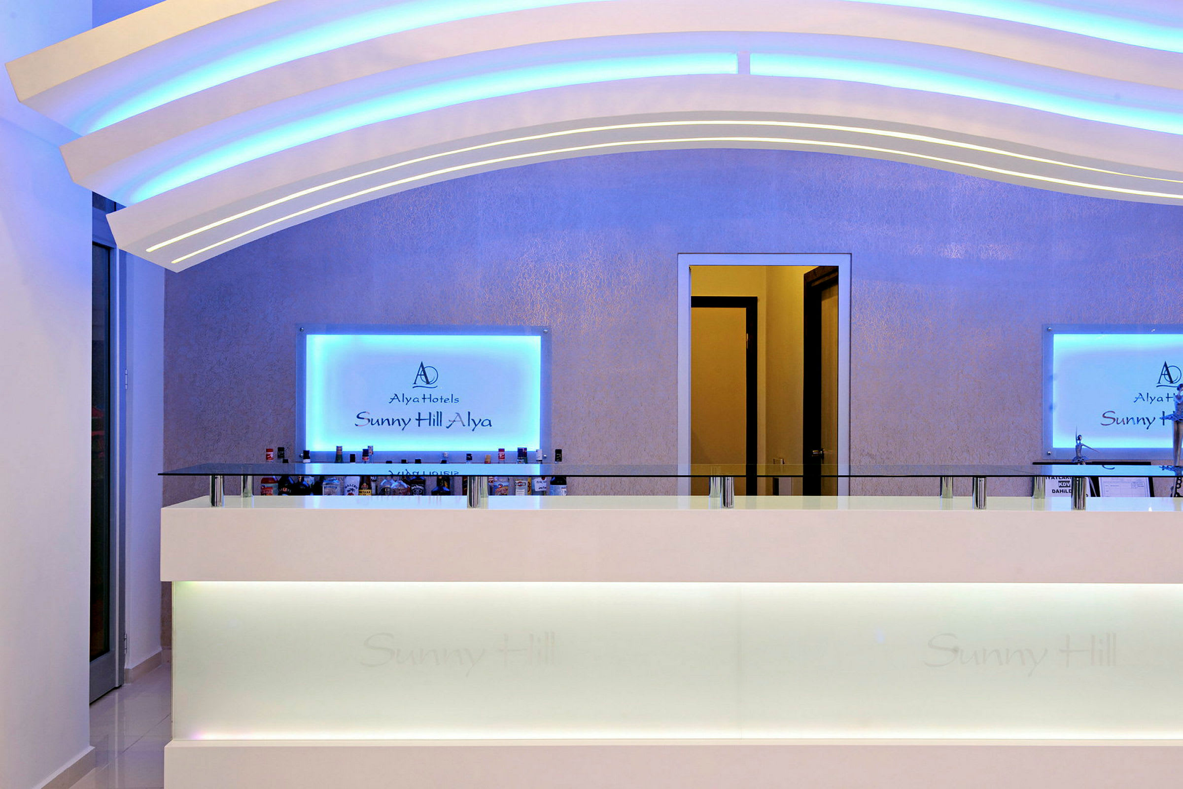 Hotellreception med en blå belyst skylt och ljus inredning. (AI-genererad text)
