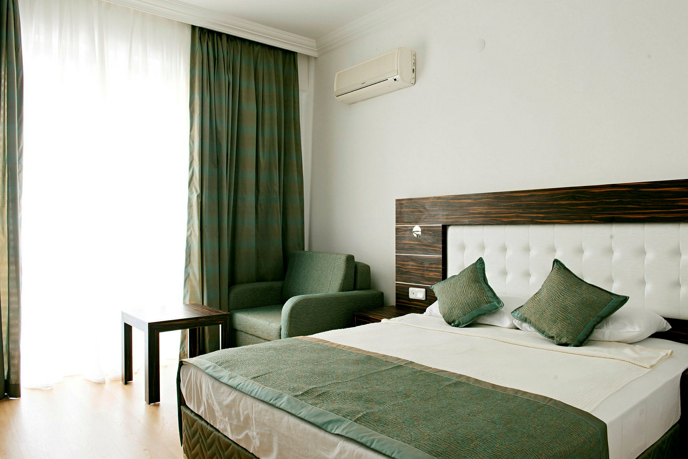 En hotellrum med en säng, stol och bord. (AI-genererad text)
