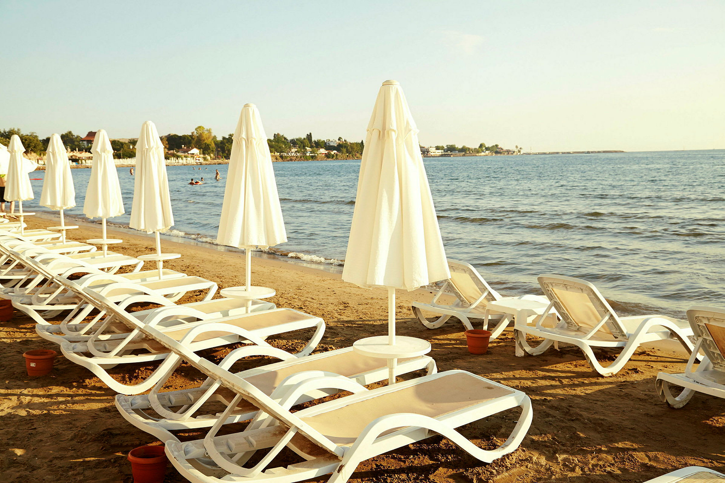 Solstolar med parasoller på en sandstrand vid havet. (AI-genererad text)