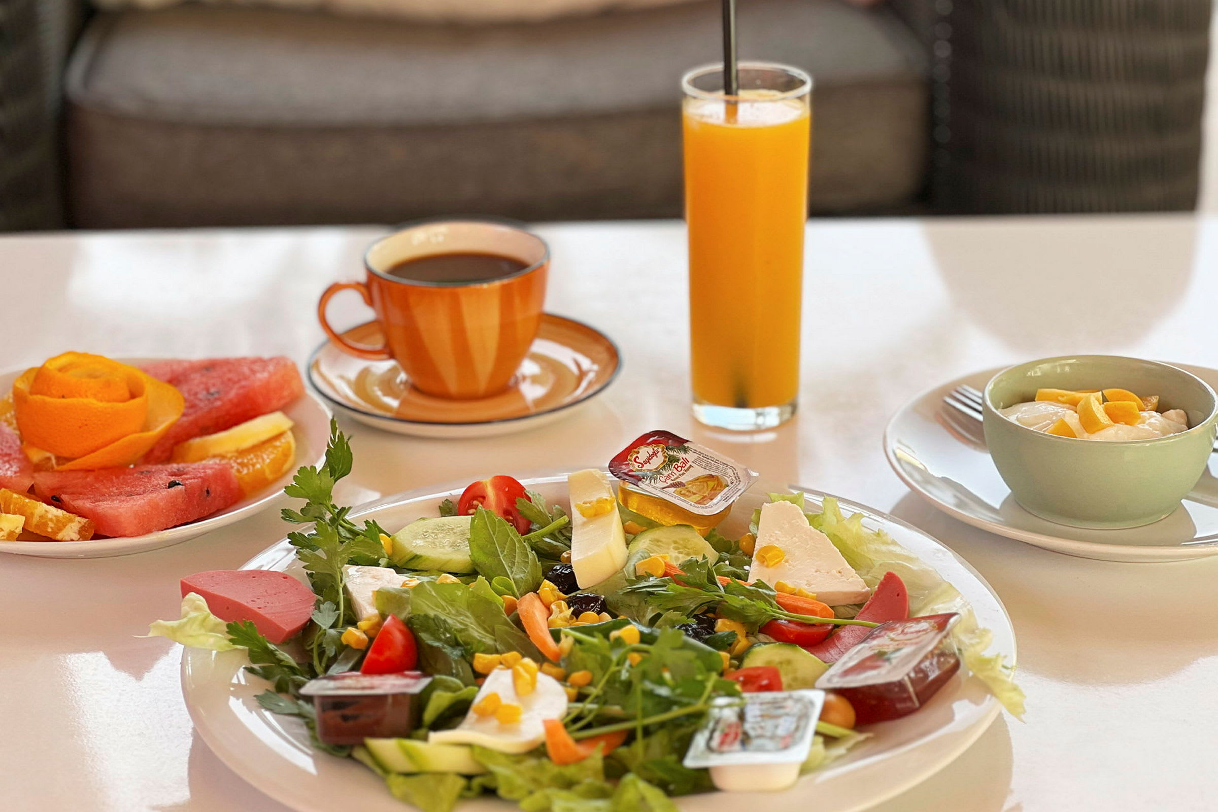 En frukost med sallad, frukt, juice, kaffe och yoghurt. (AI-genererad text)