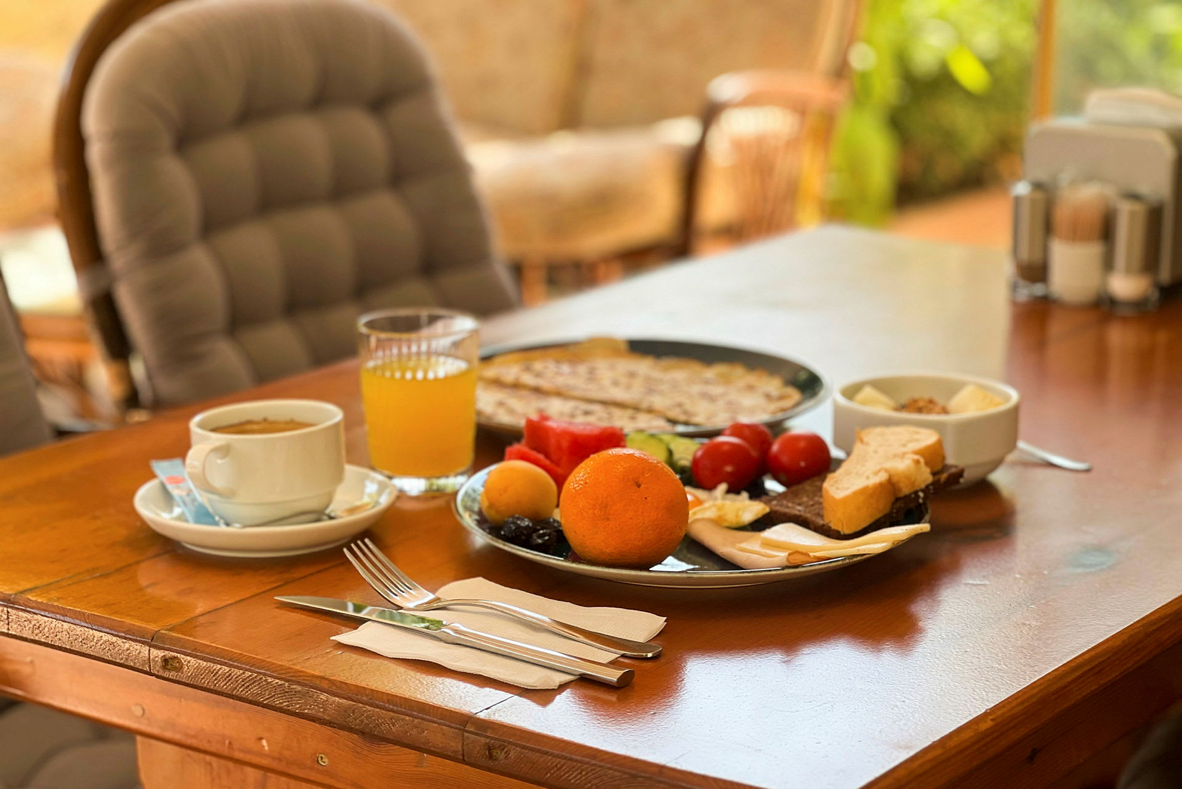 Frukost med apelsin, juice, bröd och grönsaker på bordet. (AI-genererad text)