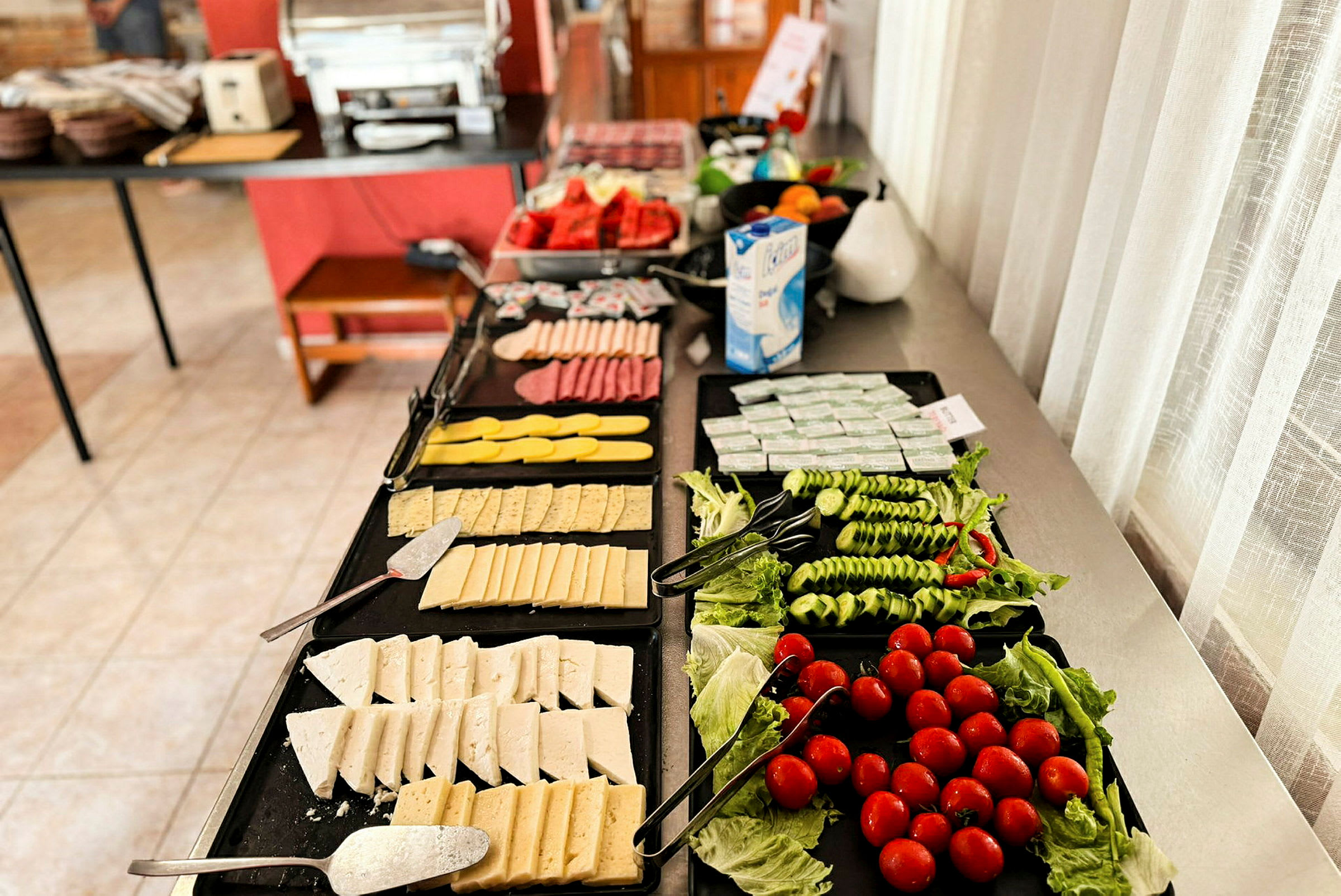 En frukostbuffé med ost, grönsaker och andra tillbehör. (AI-genererad text)