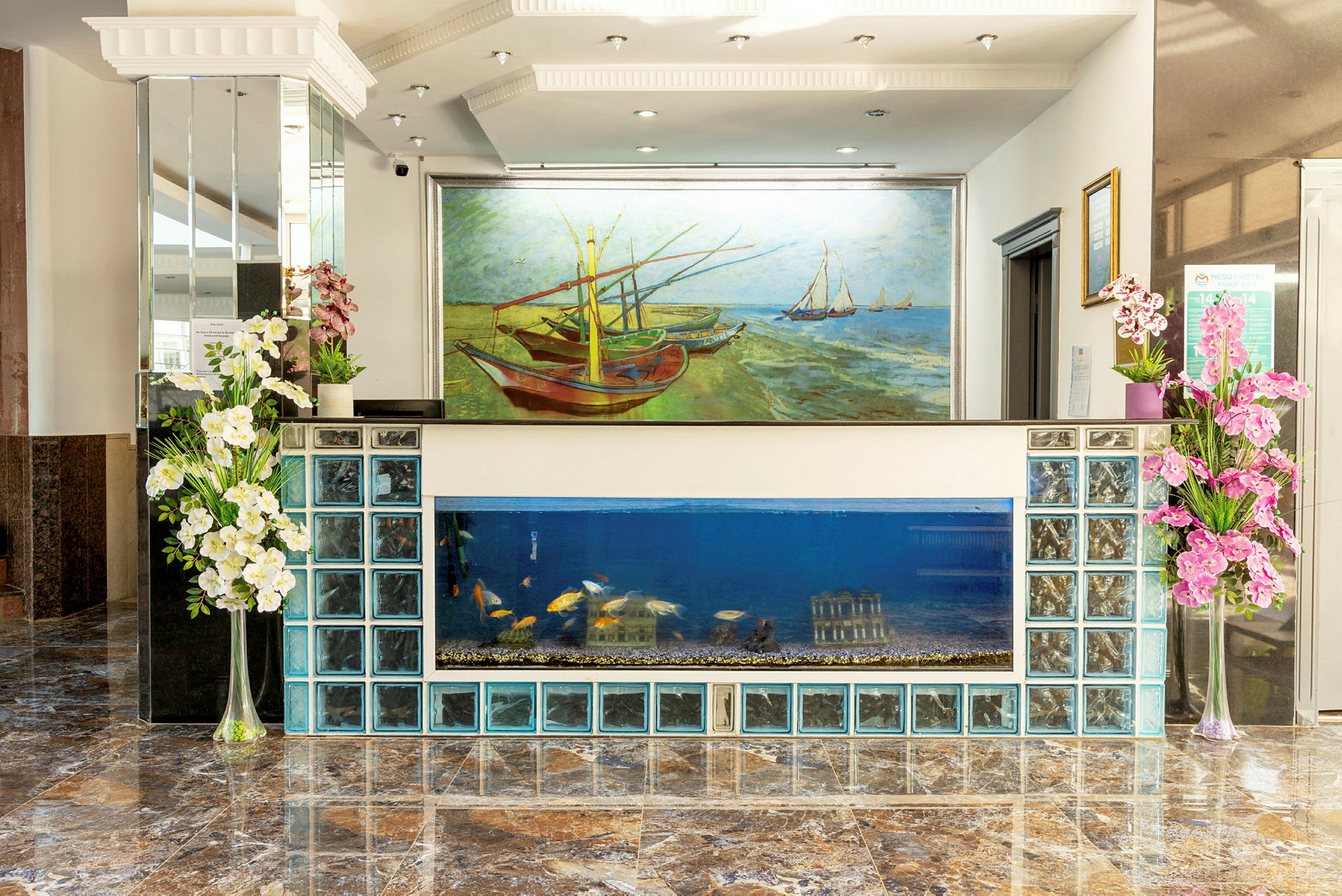 Hotelllobby med reception bestående av glasblock och akvarium, samt en stor målning av båtar på en strand. (AI-genererad text)