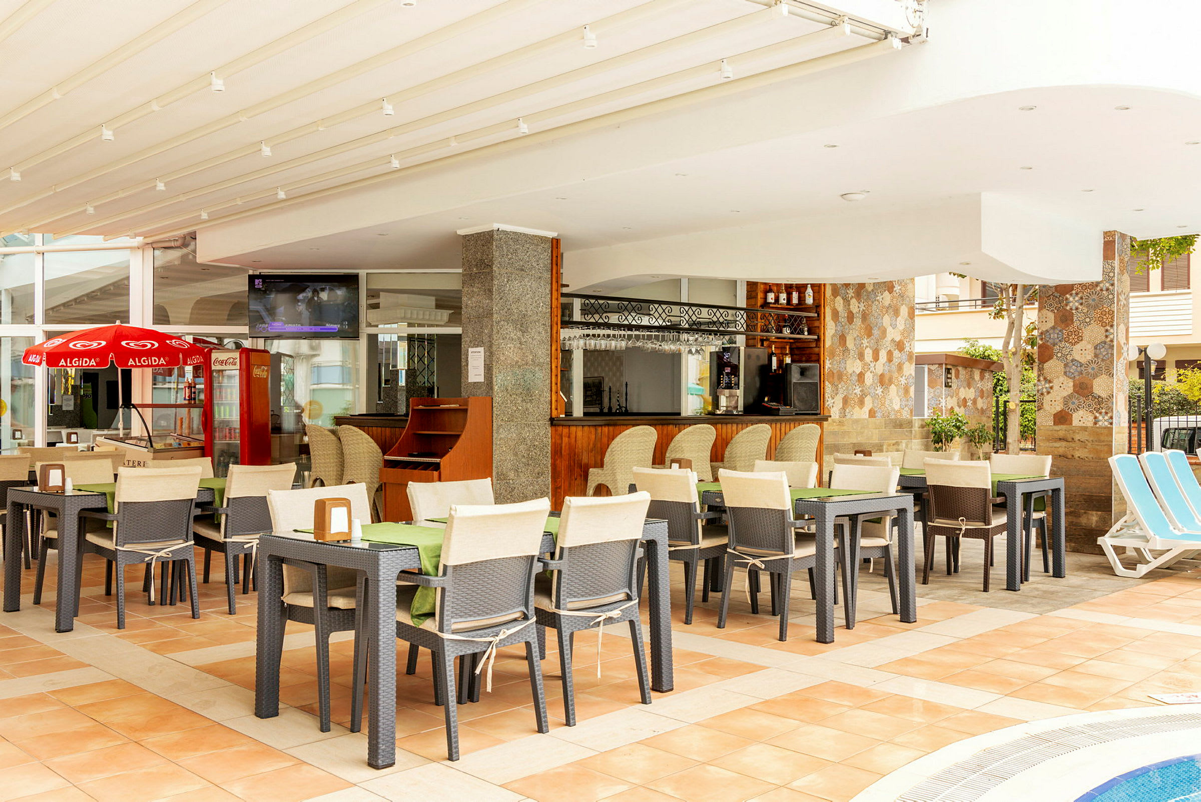 Restaurang med uteservering och bar, omgiven av stolar och bord. (AI-genererad text)