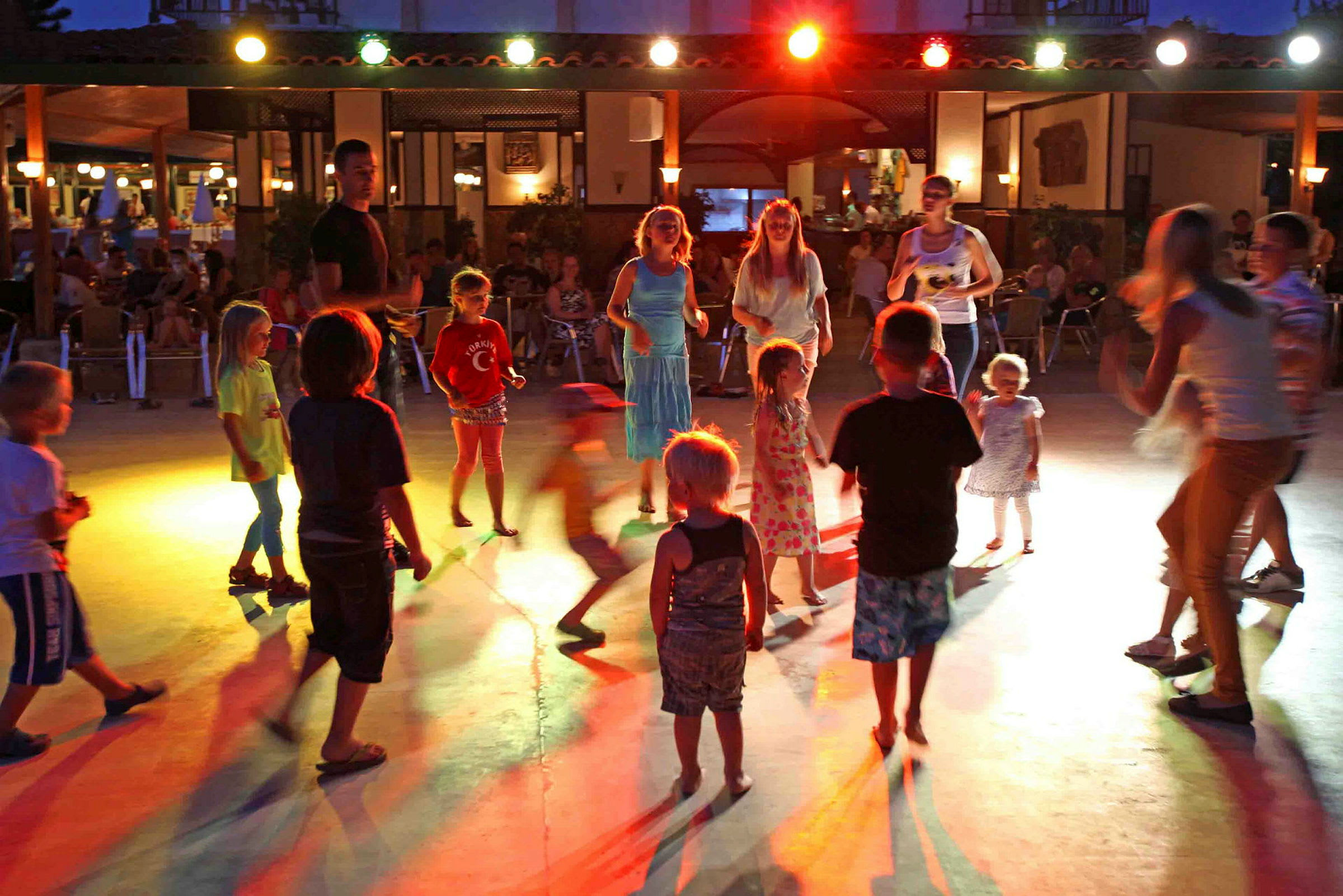 Barn dansar på en upplyst yta under kvällstid. (AI-genererad text)