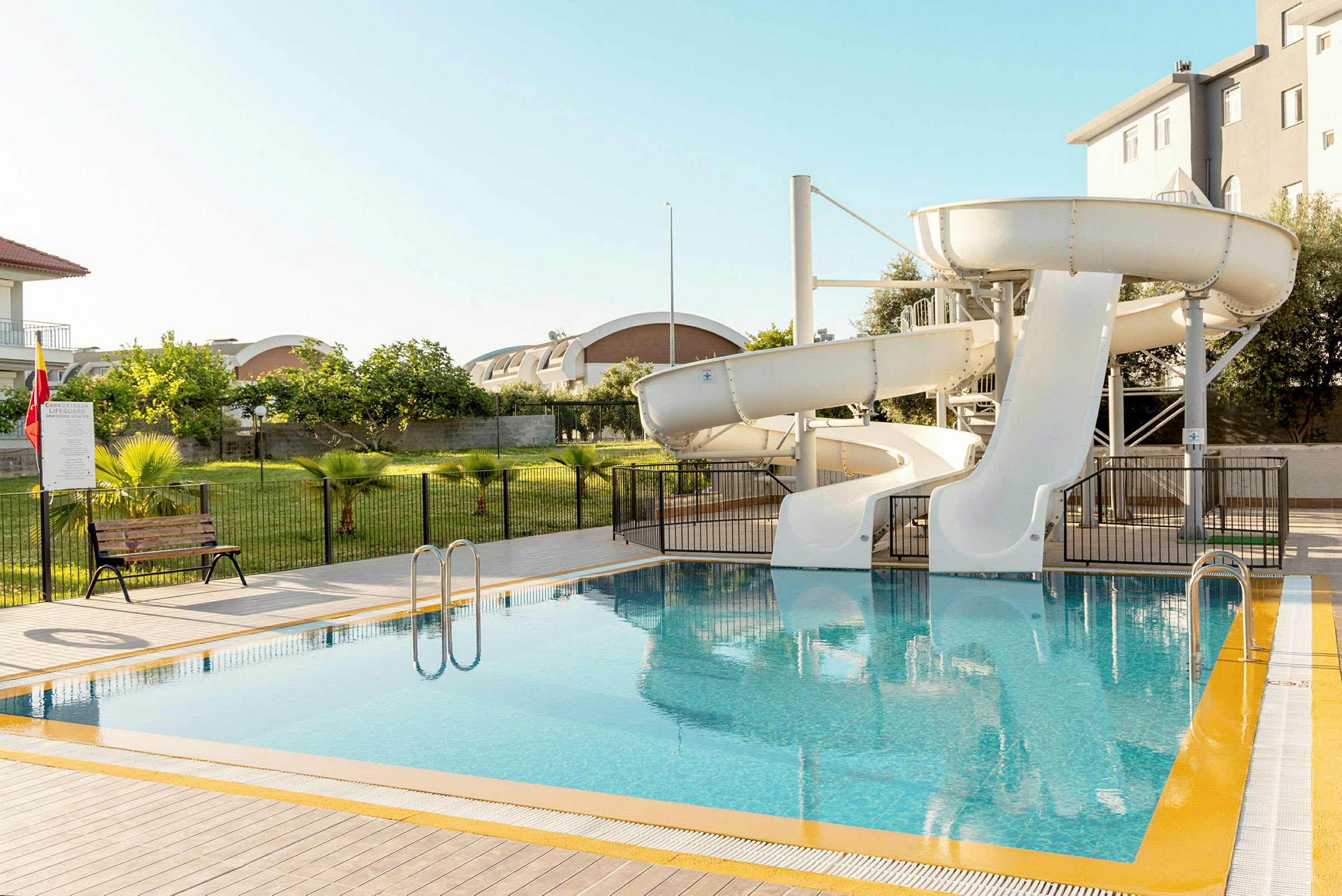 En pool med två vita vattenrutschbanor. (AI-genererad text)