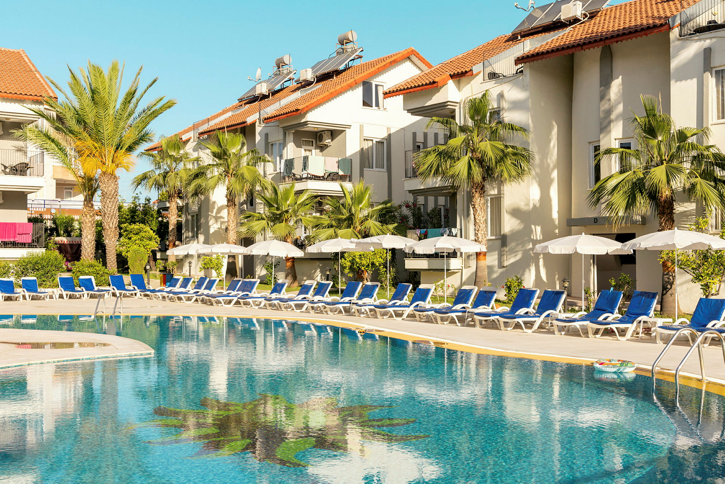 Utomhuspool vid hotell med solstolar och parasoller. (AI-genererad text)