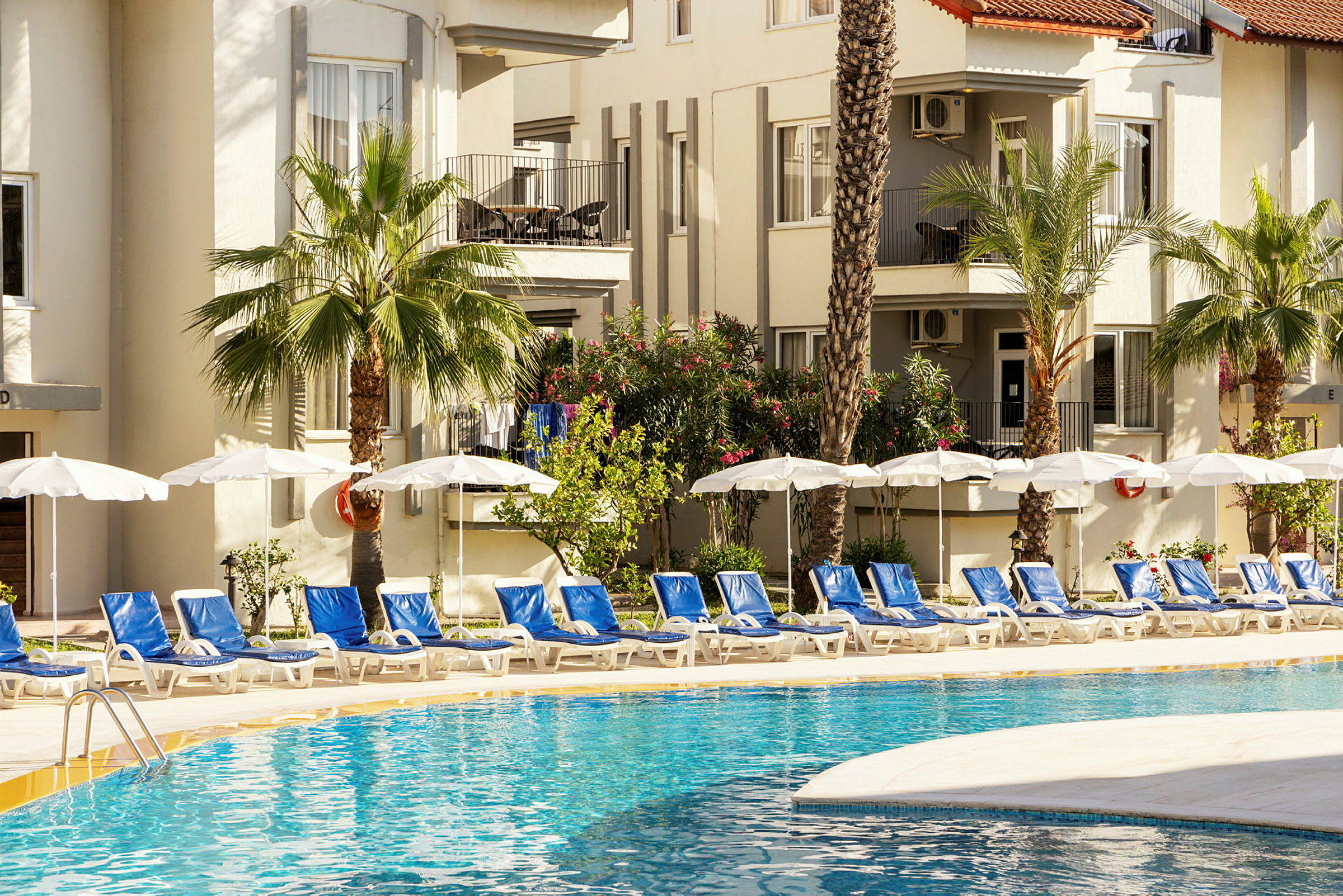 En pool med solstolar och parasoller vid ett hotell. (AI-genererad text)