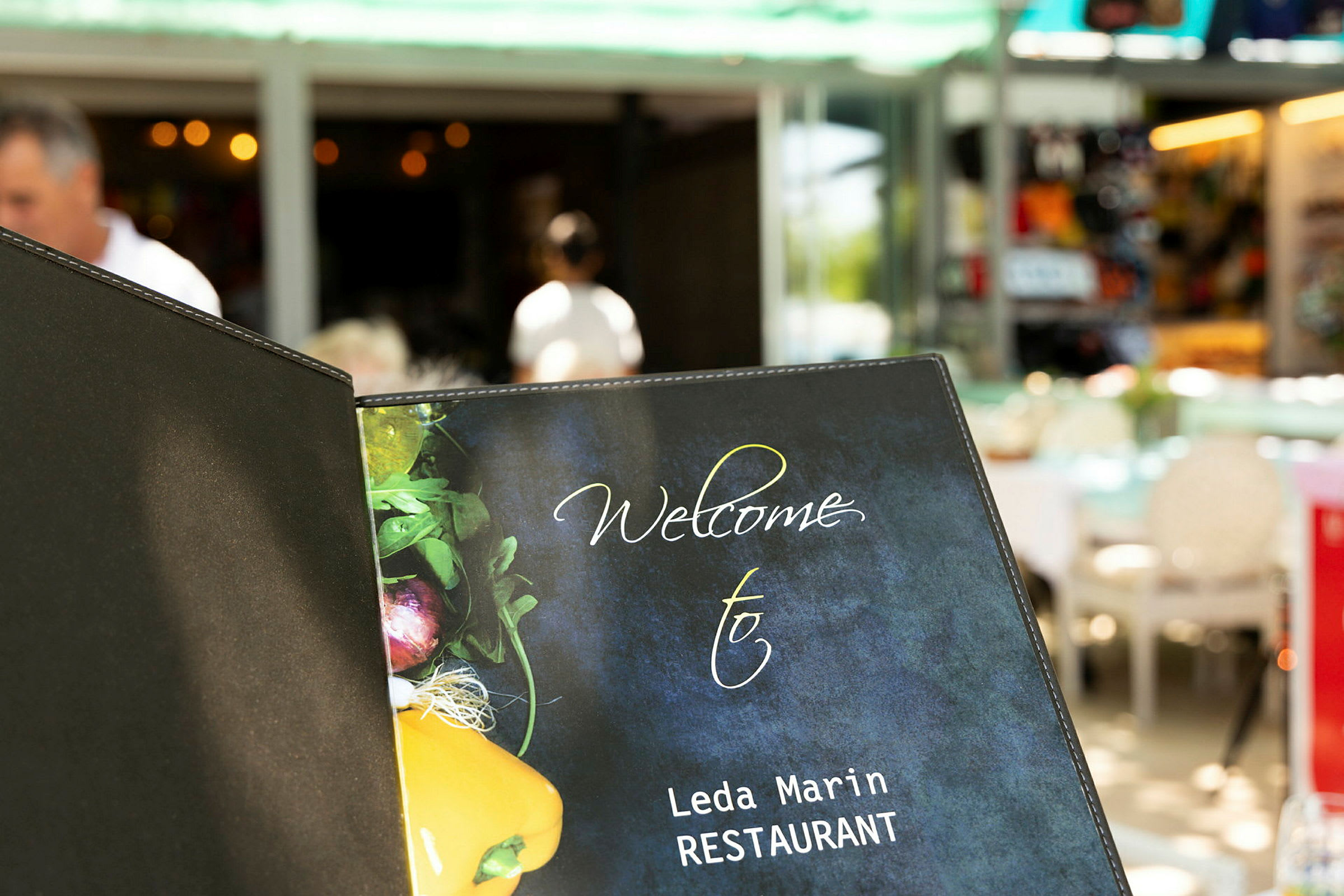 Ett restaurangmenyomslag med texten 'Welcome to Leda Marin RESTAURANT' och en bild av grönsaker på framsidan. (AI-genererad text)